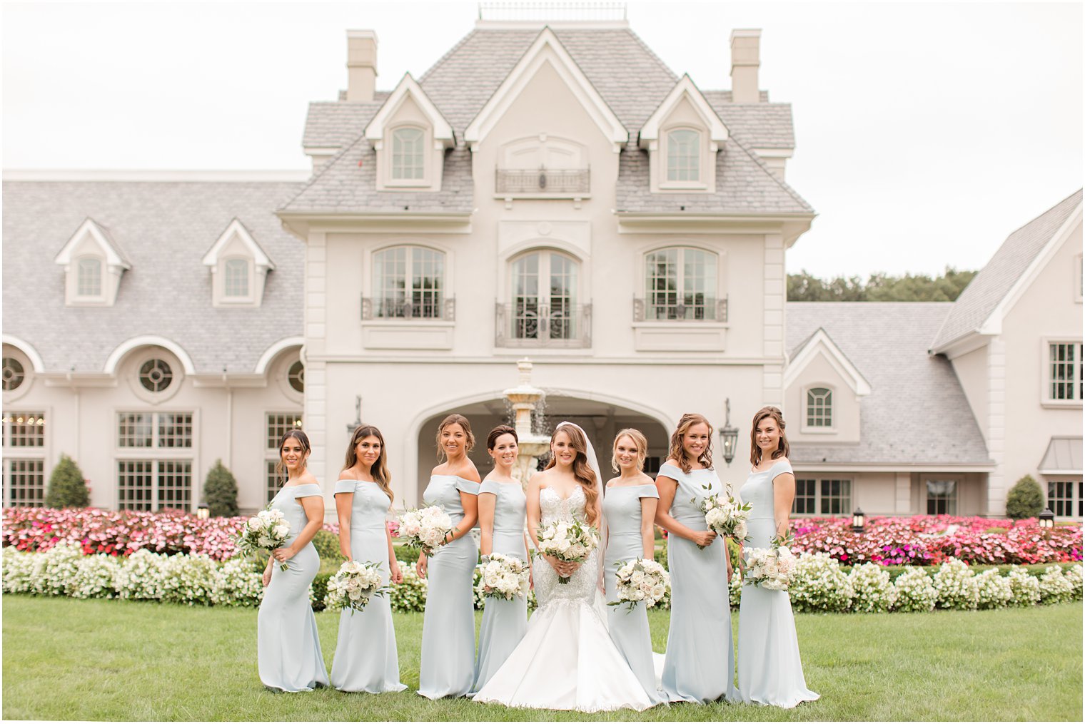 bride poses with bridesmaids in pale blue gowns at Park Chateau Estate