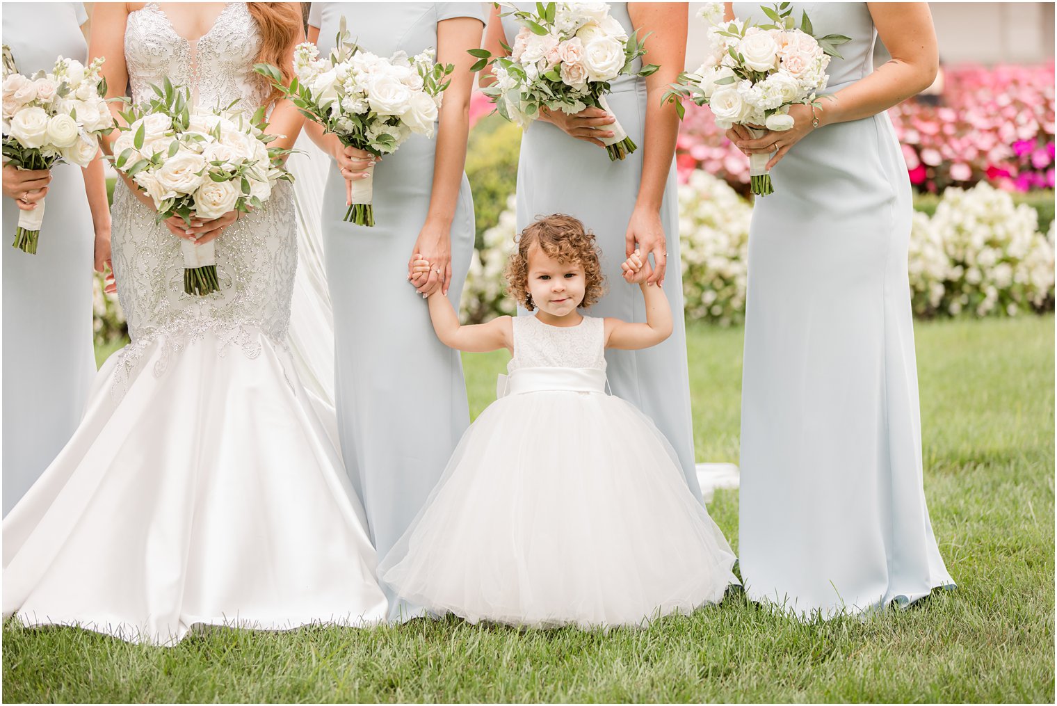 bride poses with bridesmaids in blue gowns holds flower girl's hands