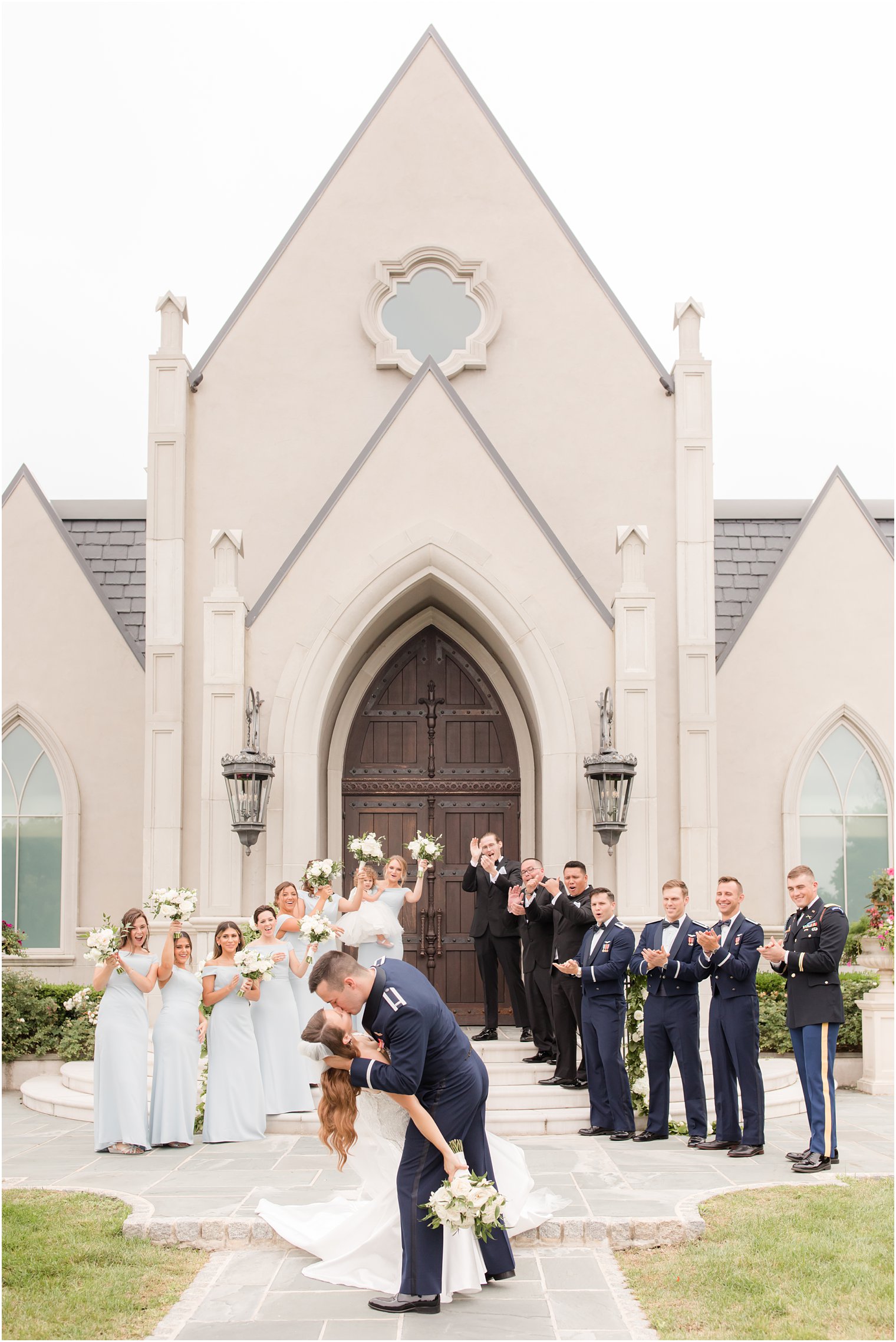 bride and groom kiss while wedding party cheers outside the chapel at Park Chateau Estate