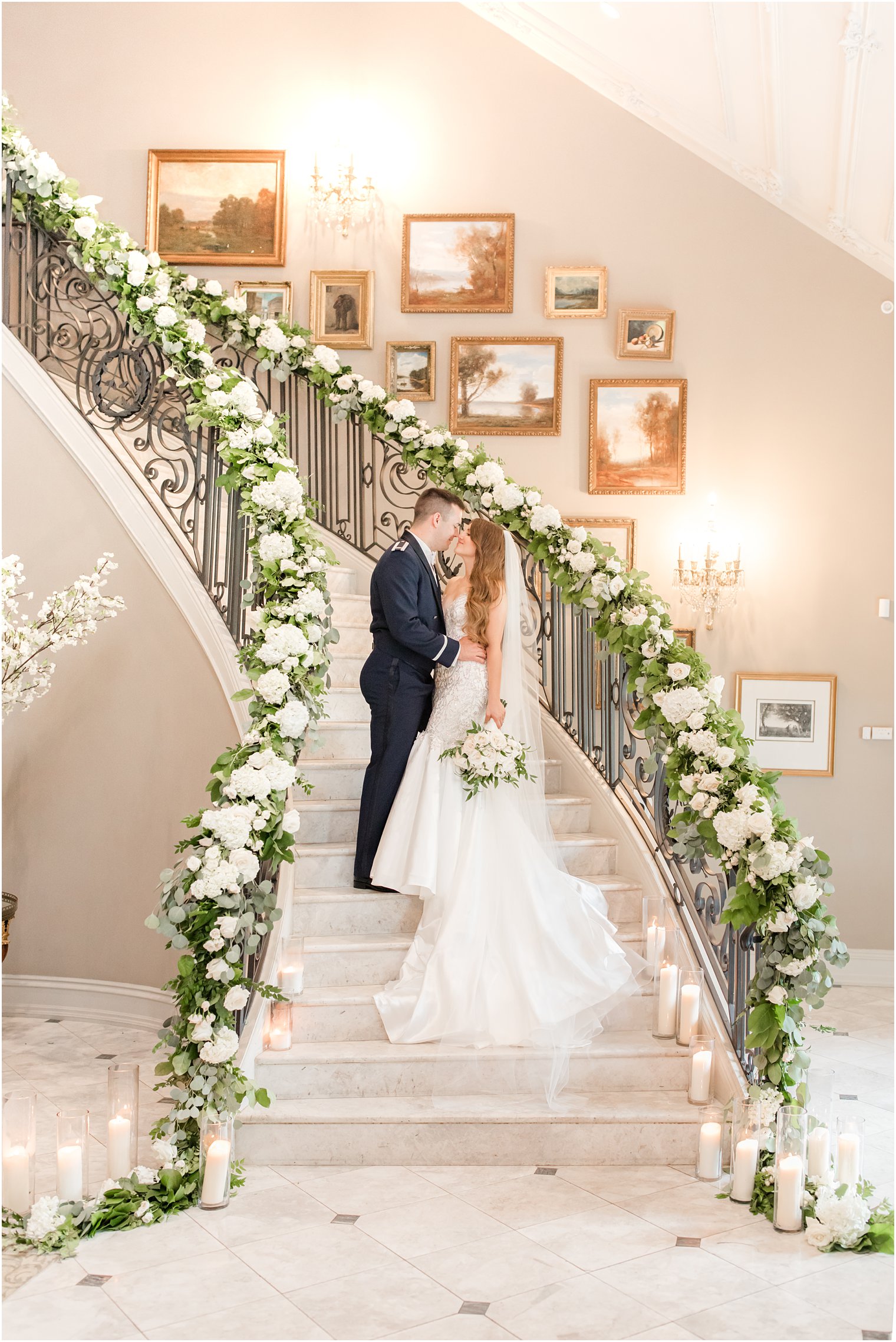 newlyweds stand on staircase with floral garland