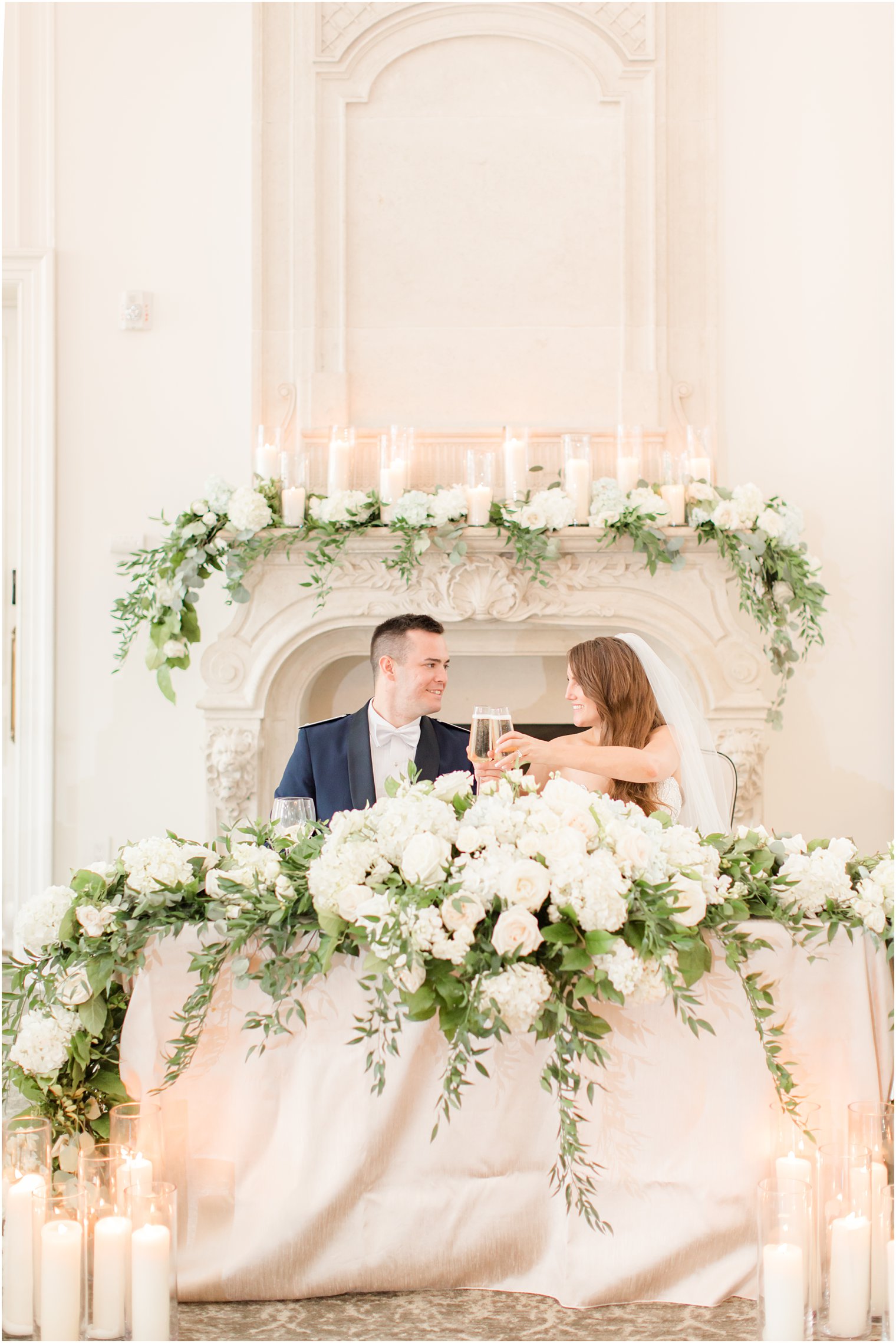 newlyweds toast champagne at sweetheart table with white roses at Park Chateau Estate