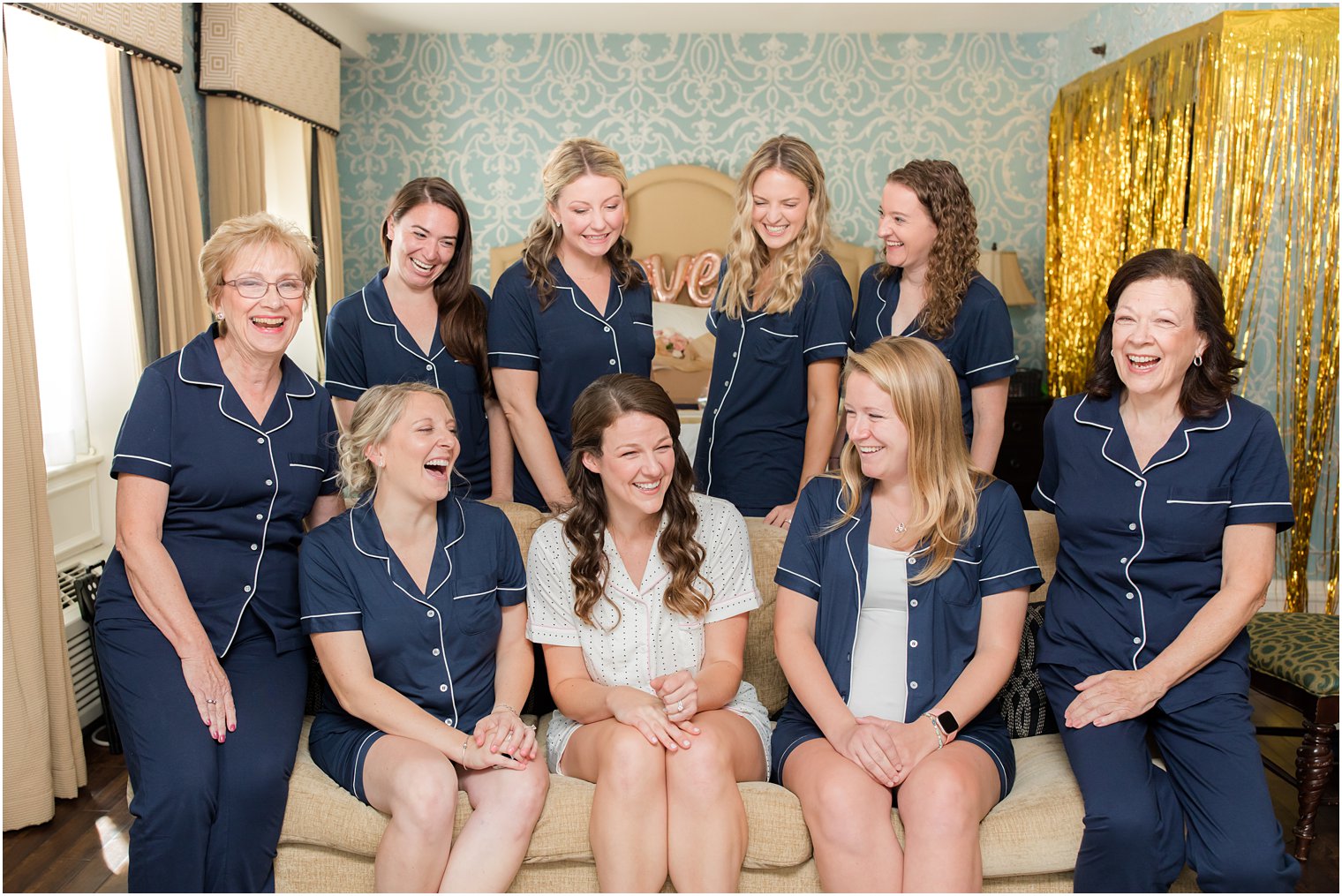bride laughs with bridesmaids and moms around her 