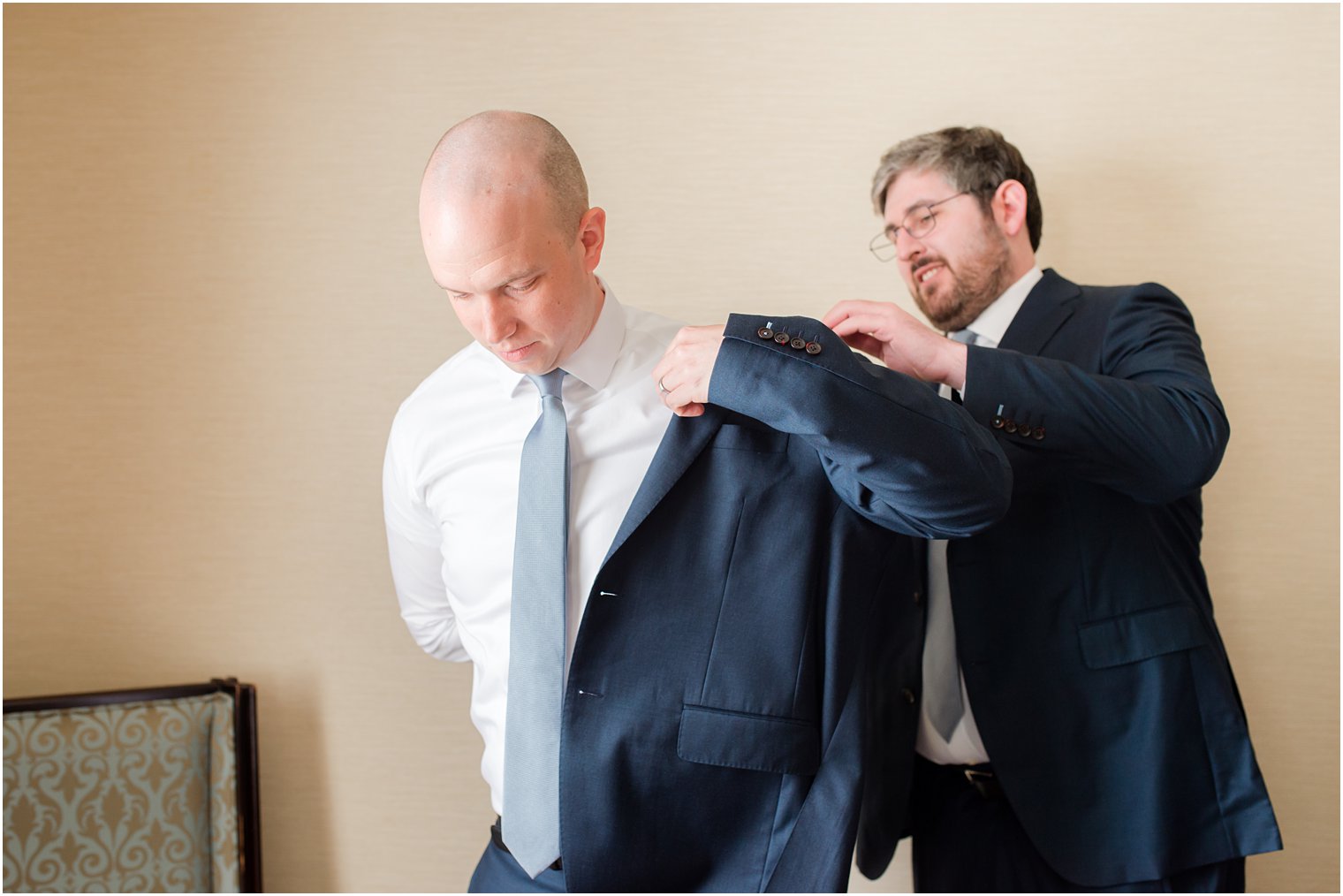 best man help groom into coat for NJ wedding day