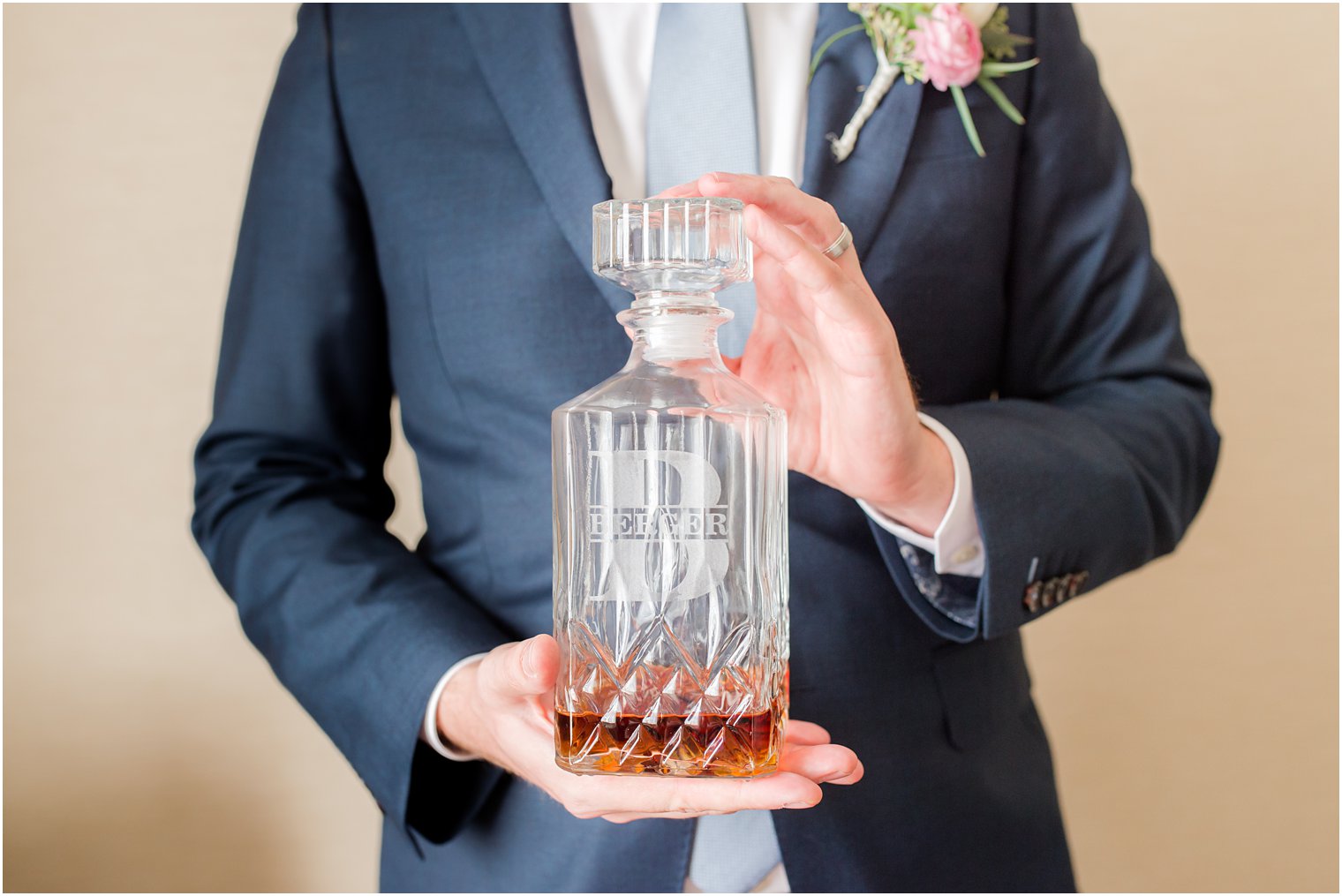 groom holds glass bottle with drink 