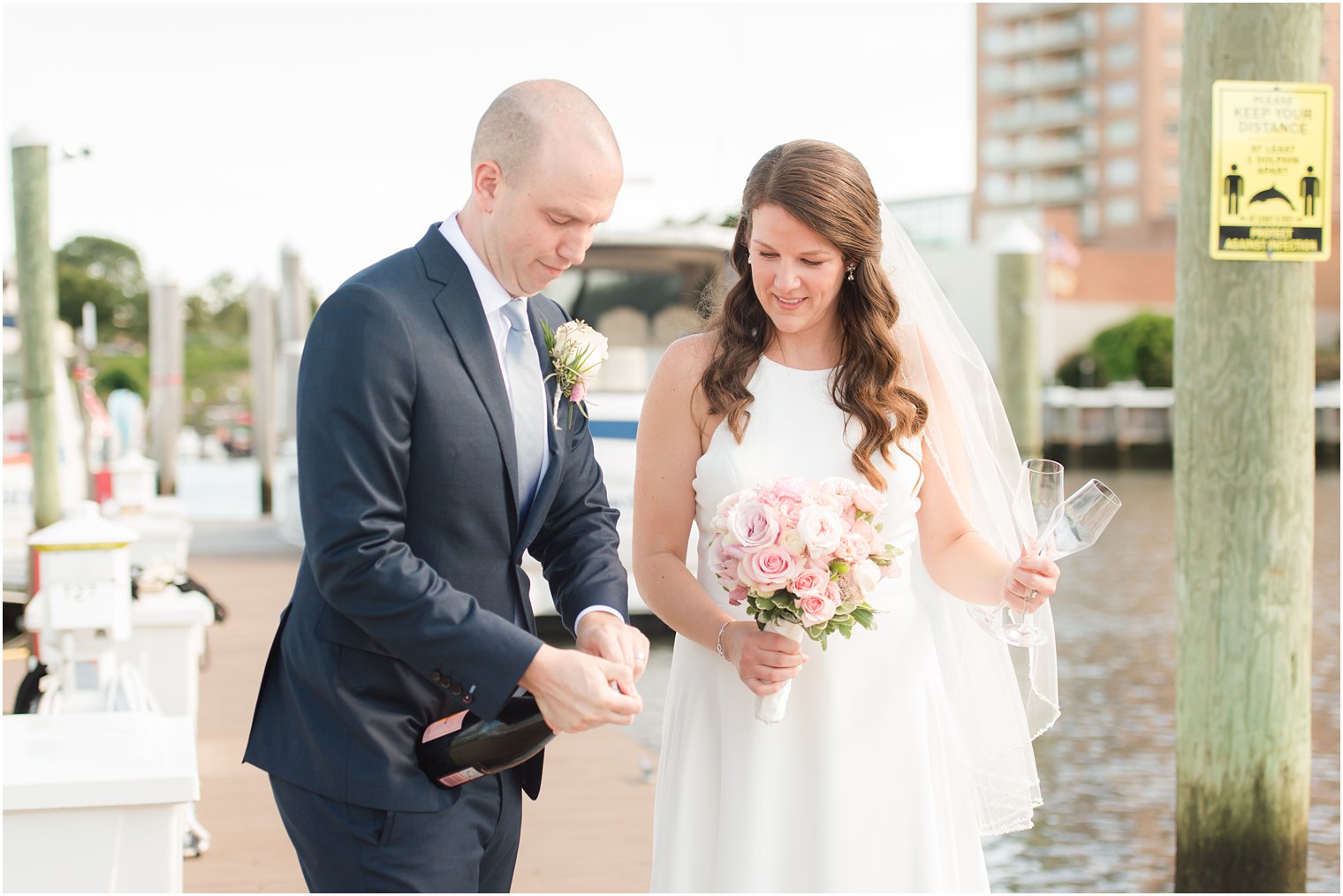 groom pops champagne during portraits on dock at Molly Pitcher Inn