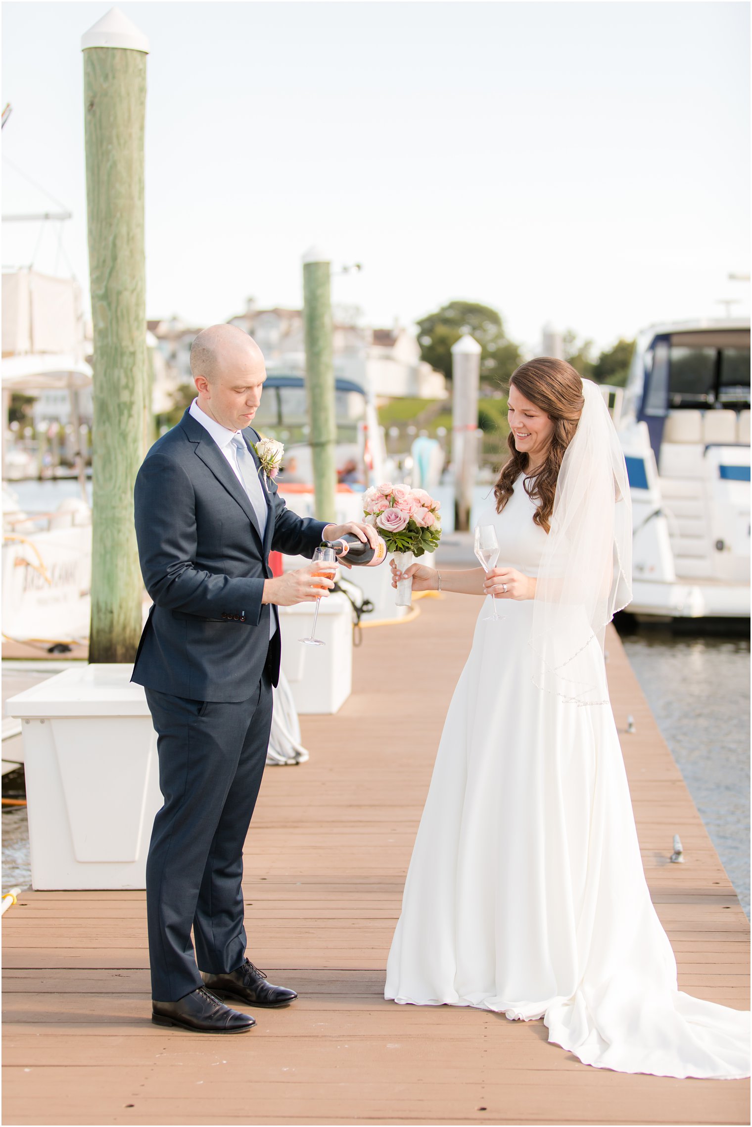 groom pours champagne for bride and groom on dock 