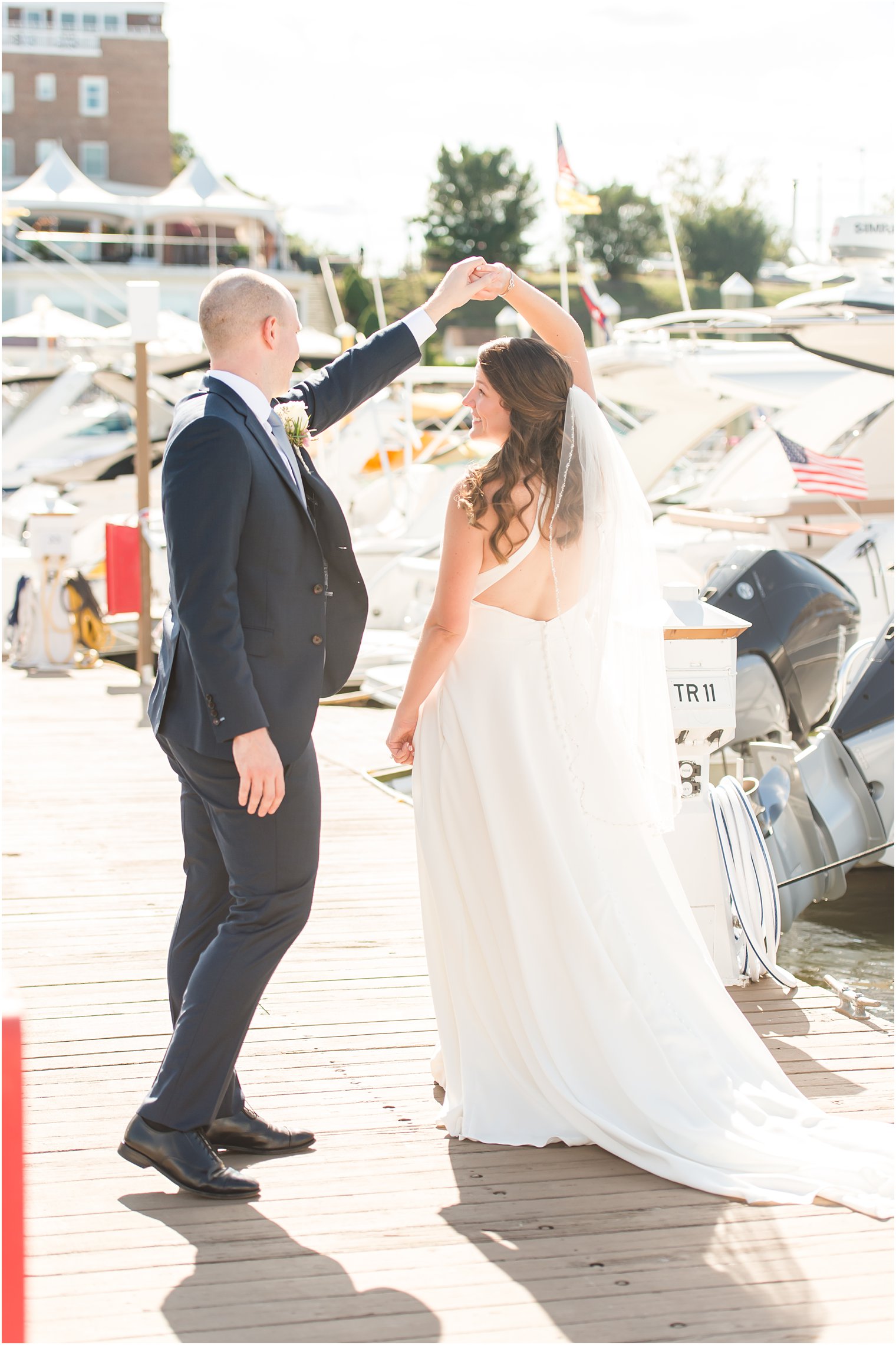 groom twirls bride during portraits on marina at Molly Pitcher Inn