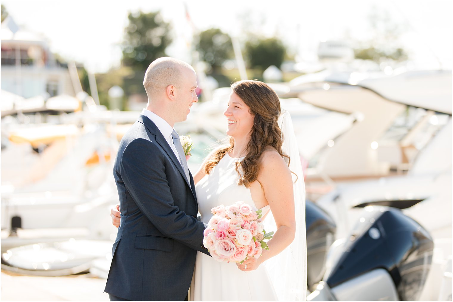 bride and groom smile, laughing on marina in Red Bank NJ