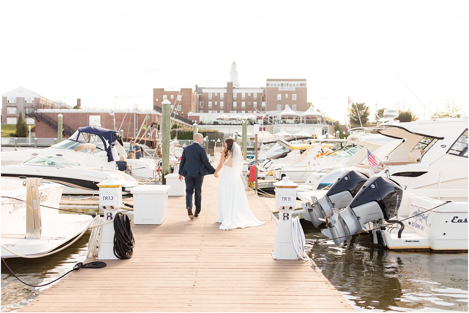 newlyweds walk down dock outside Molly Pitcher Inn