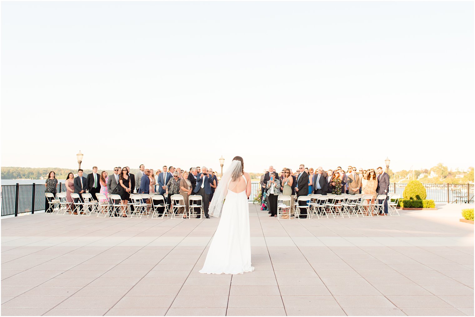 bride walks to ceremony during outdoor waterfront wedding ceremony in Red Bank NJ