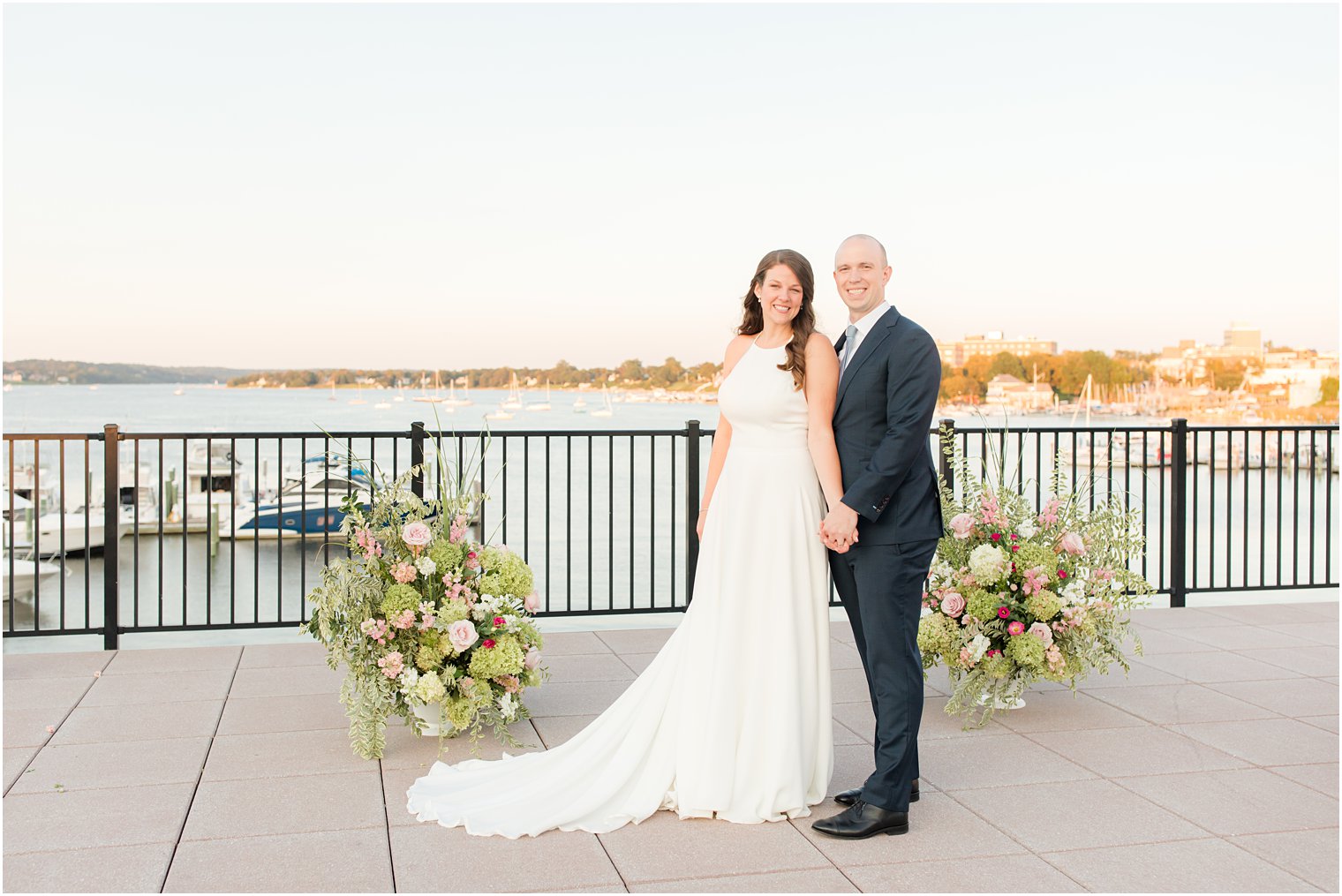 bride and groom hold hands at ceremony site overlooking the water 