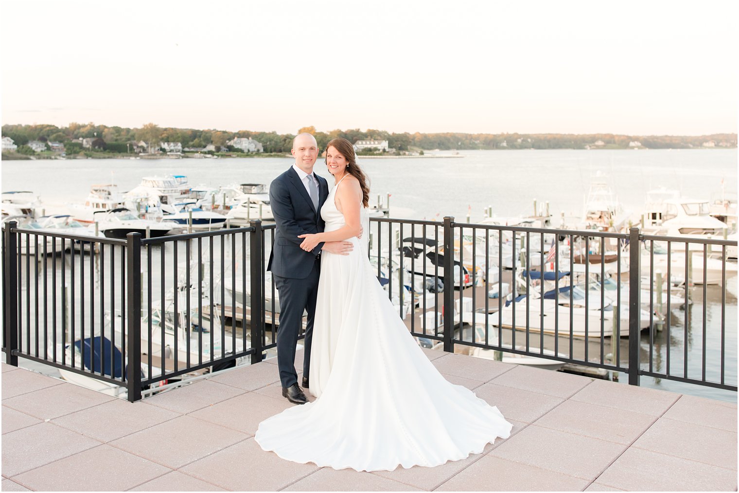 newlyweds stand on balcony overlooking marina in Red Bank NJ