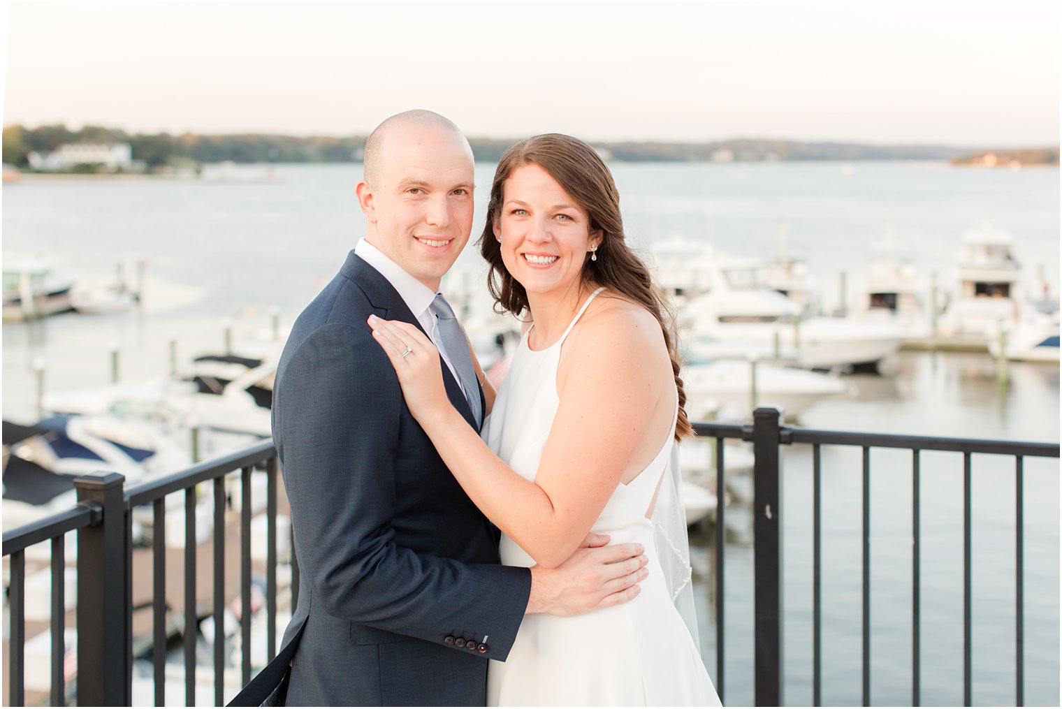 newlyweds pose on Molly Pitcher Inn balcony overlooking water 