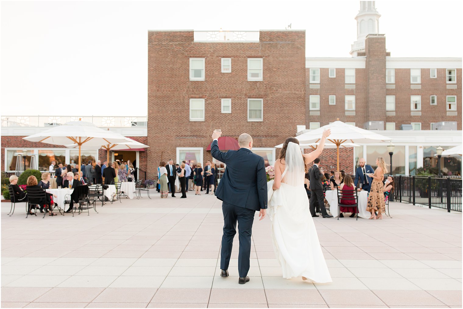 bride and groom waves to guests on patio during cocktail hour at Molly Pitcher Inn