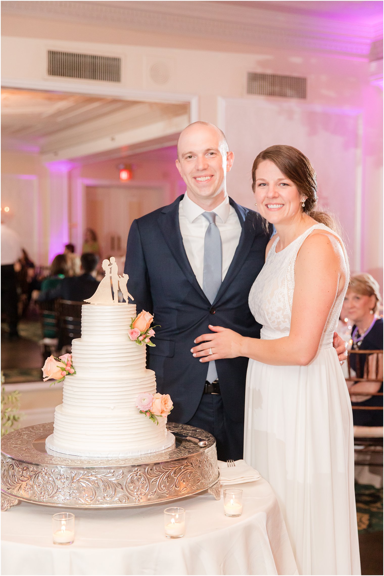 newlyweds pose by wedding cake during Red Bank NJ wedding reception
