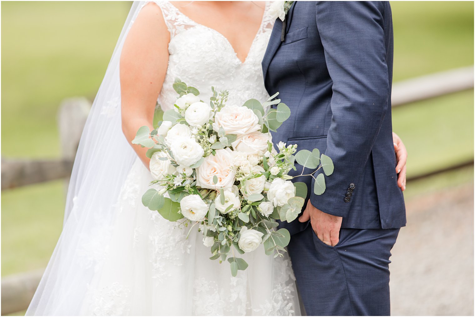 bride and groom hug while bride holds bouquet of white and pink flowers