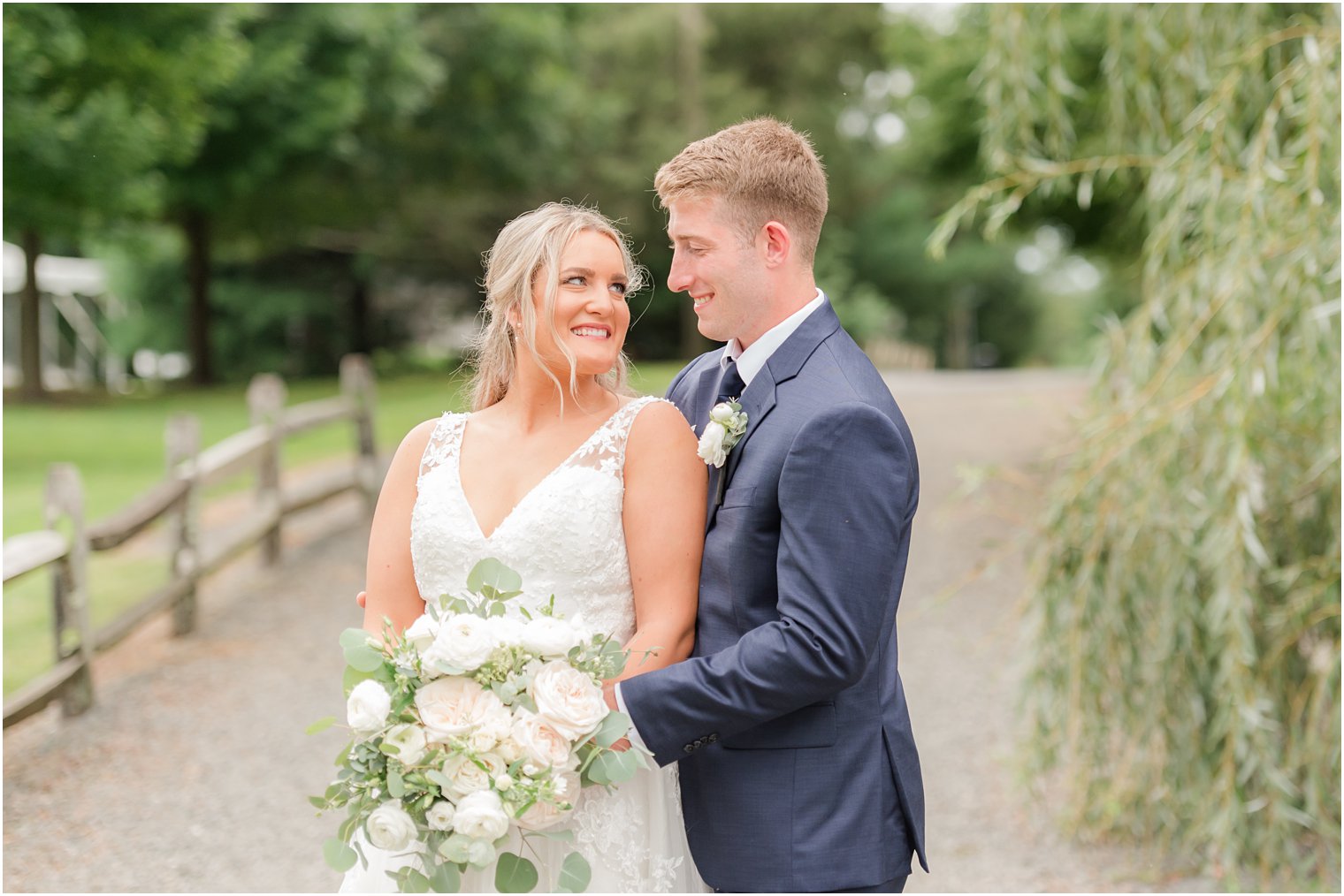 groom hugs bride with bouquet of ivory flowers