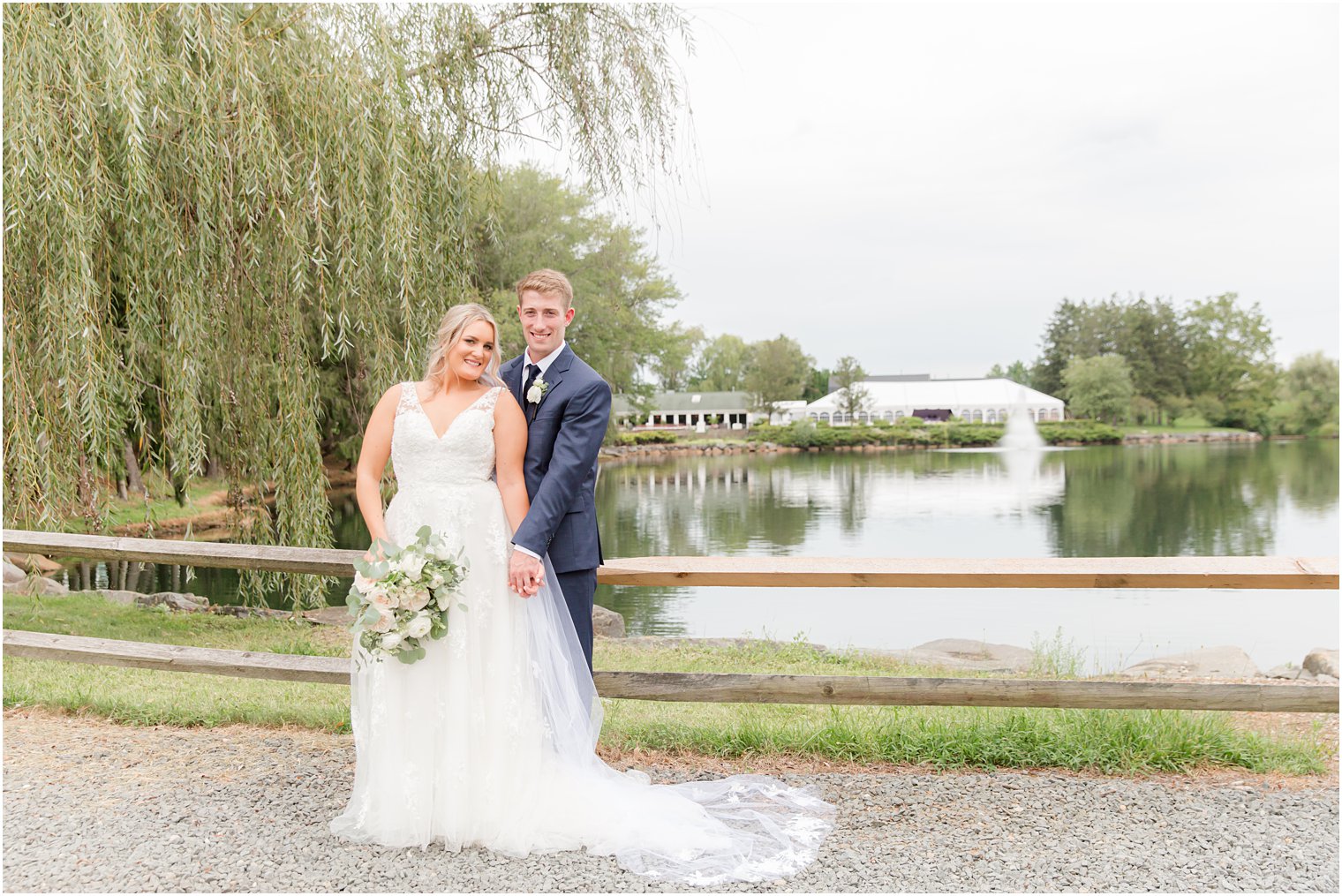 bride and groom pose by weeping willow at Windows on the Water at Frogbridge