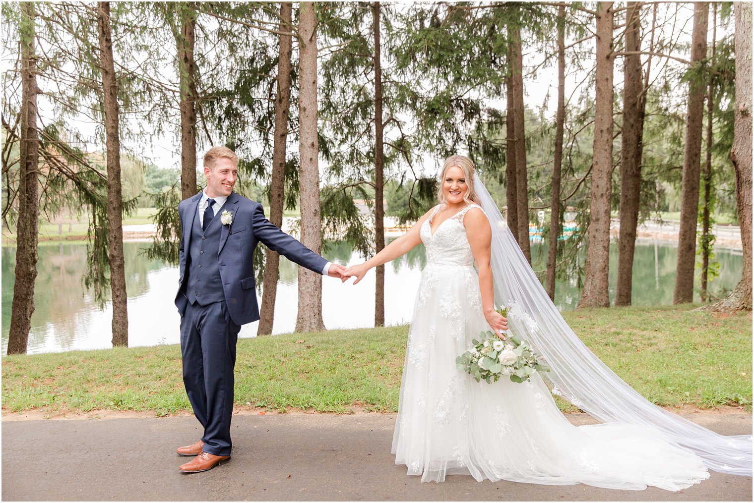 groom leads bride through pathway at Windows on the Water at Frogbridge