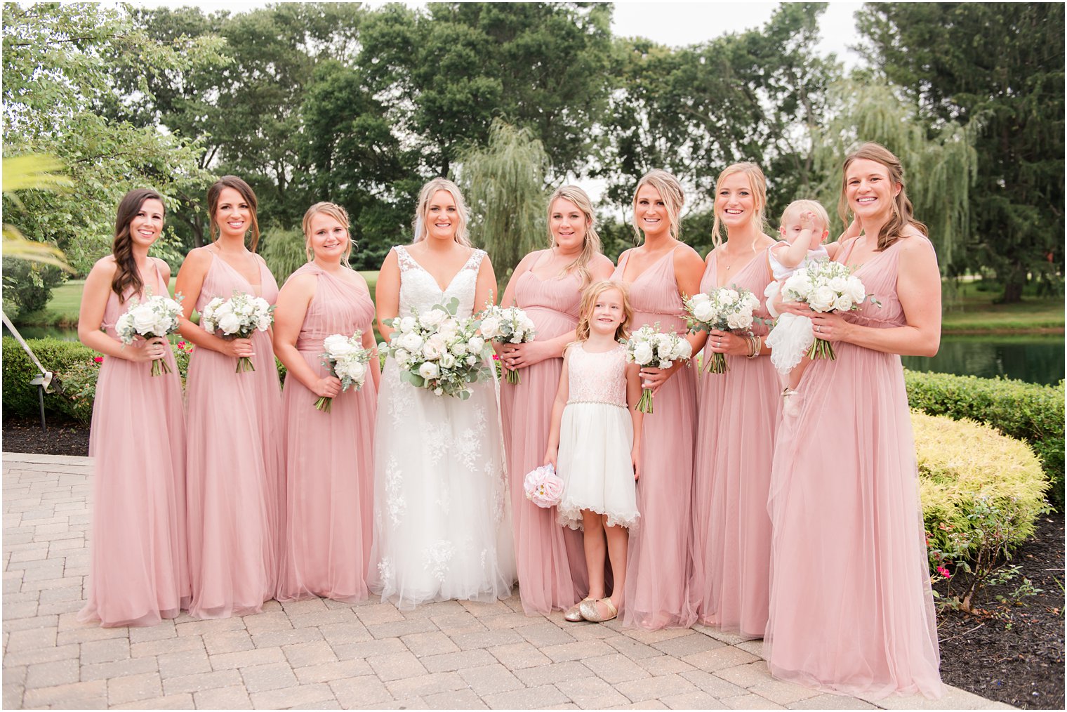 bride poses with bridesmaids in pink gowns