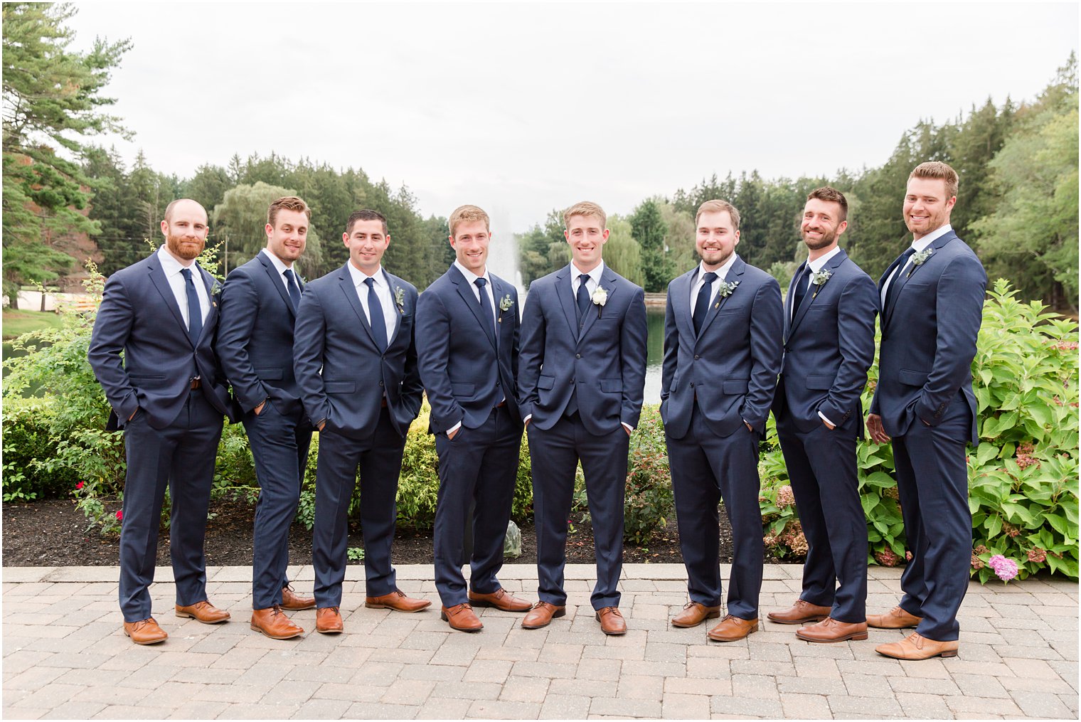 groomsmen in navy suits pose by groom with hands in pocket