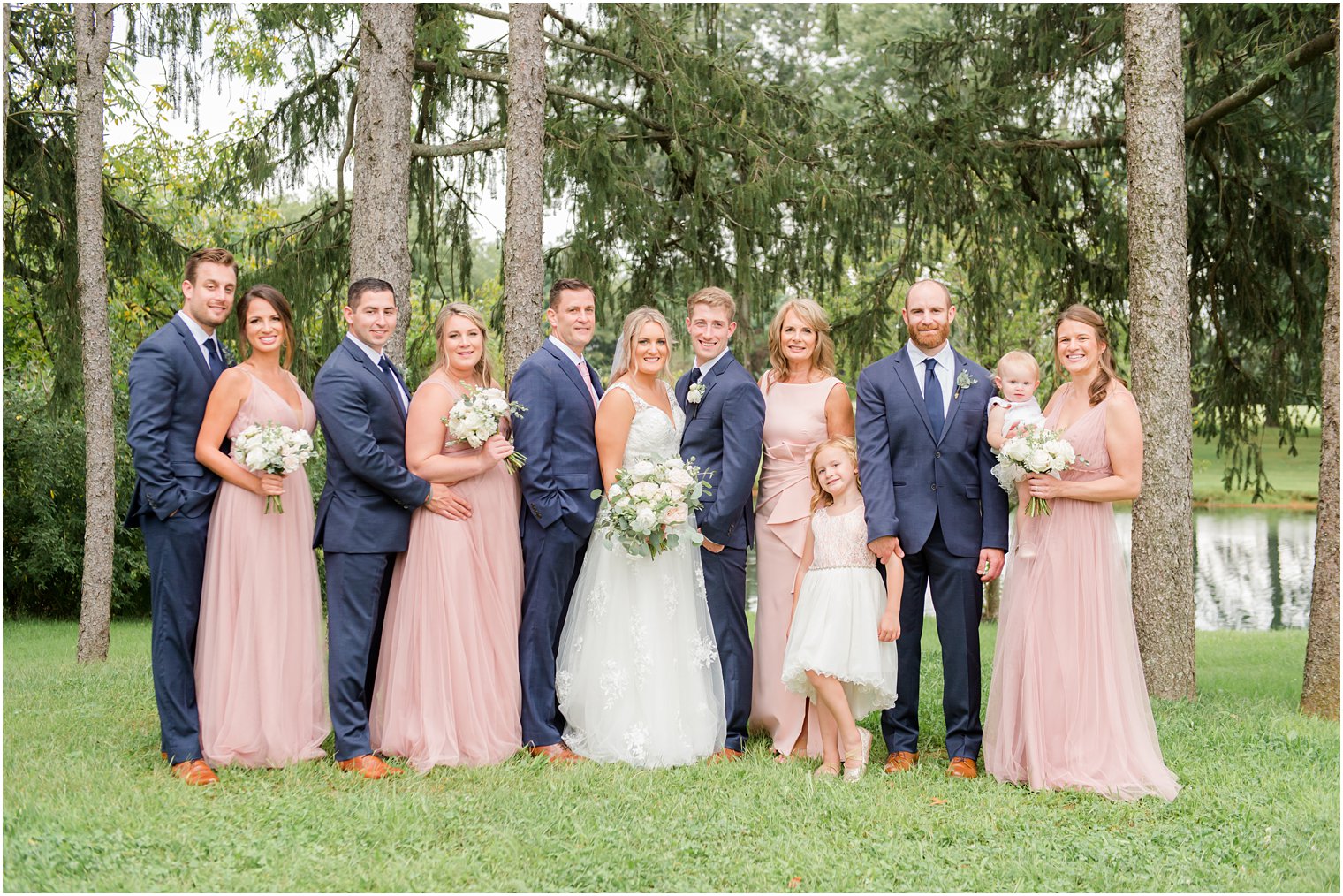 bride and groom pose with wedding party in pink and navy