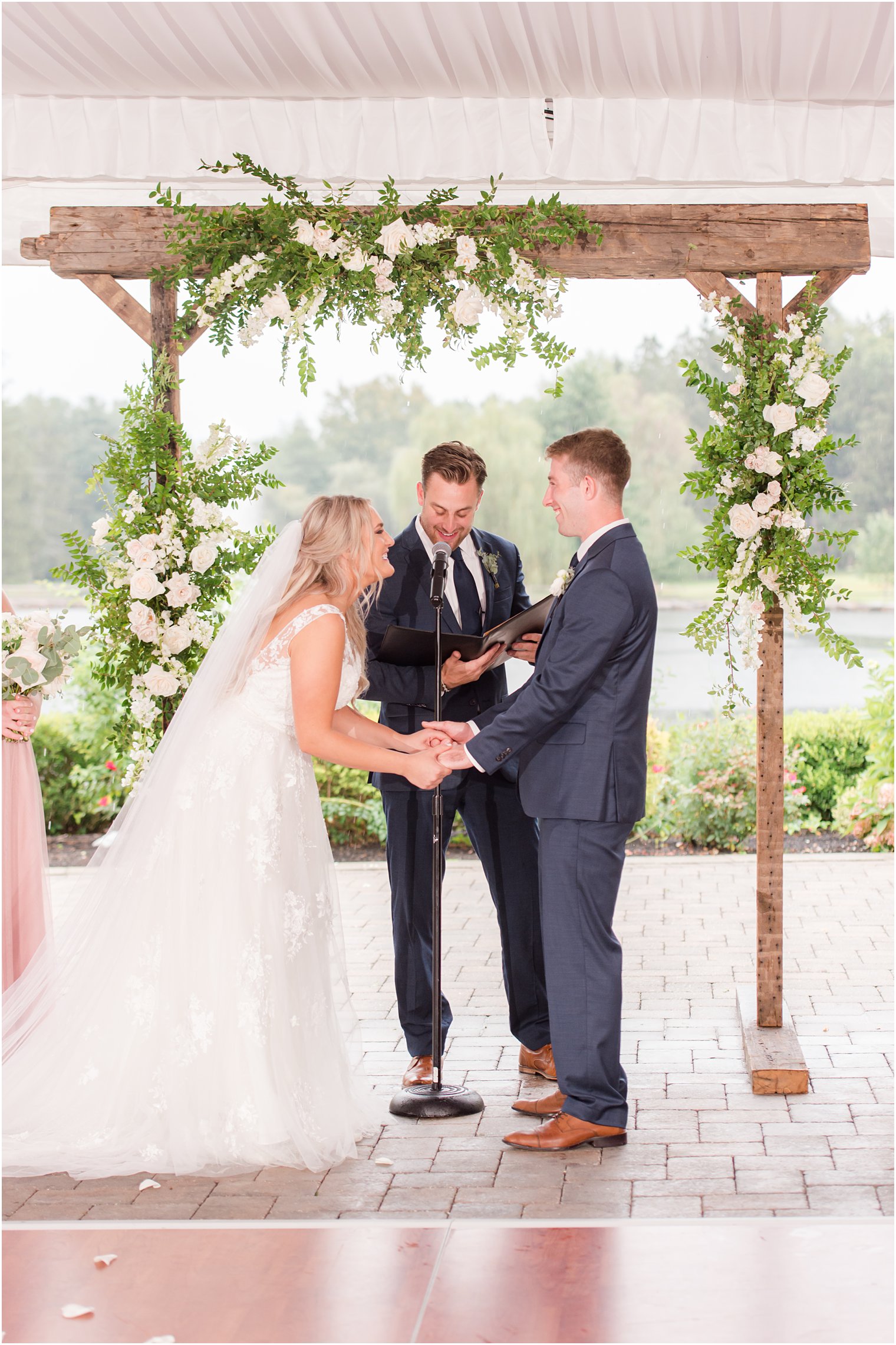 bride and groom laugh during tented wedding ceremony at Windows on the Water at Frogbridge