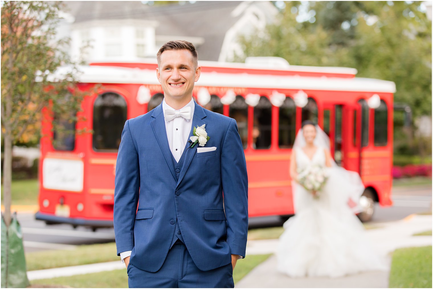 bride approaches groom for first look outside red trolley
