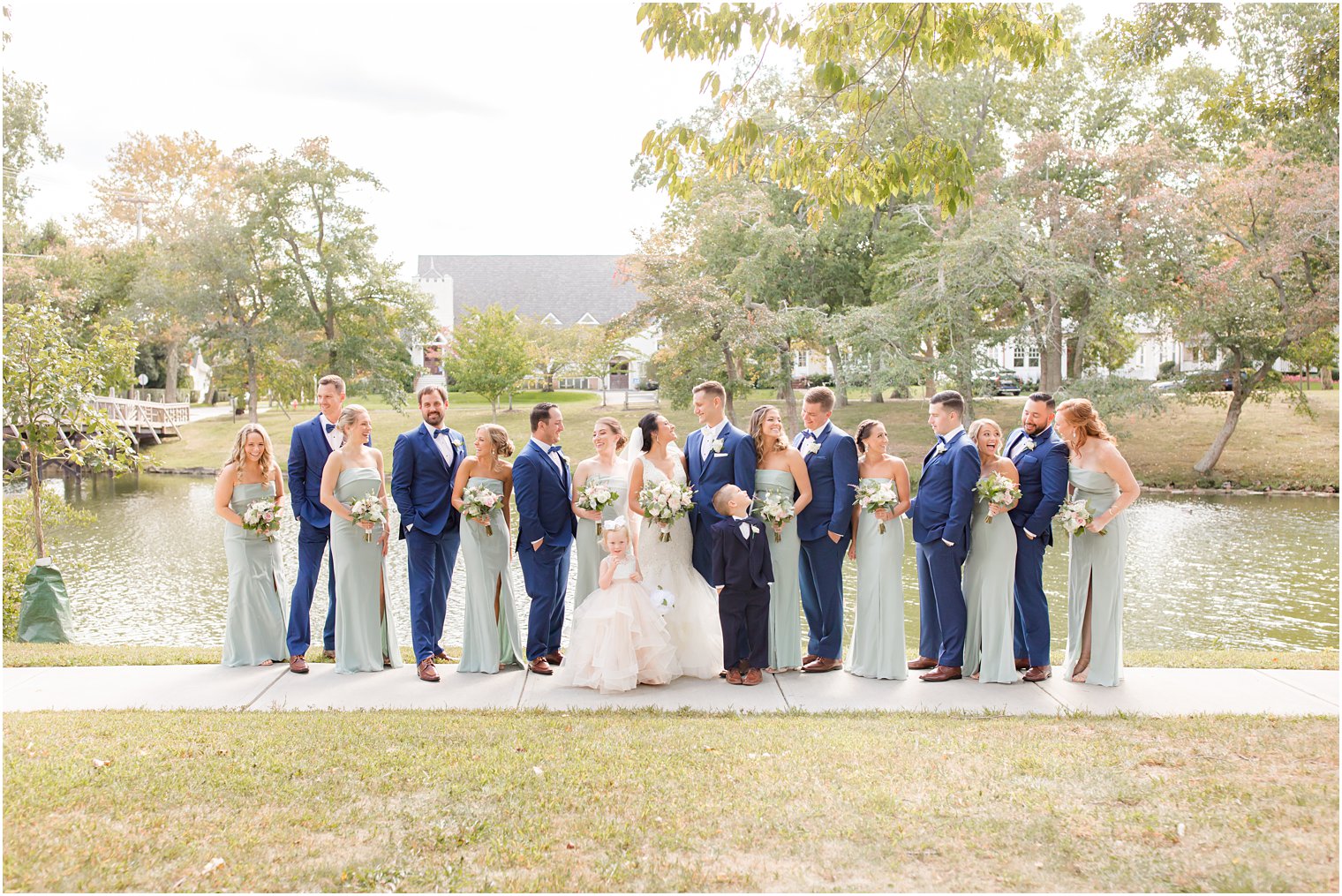 newlyweds pose with wedding party in sage green and navy blue