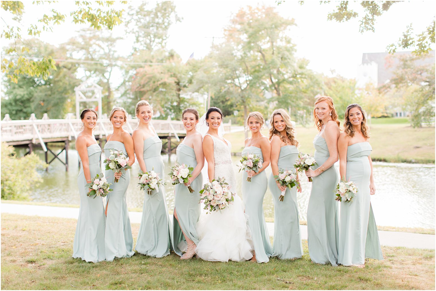 bride poses with bridesmaids in sage green gowns