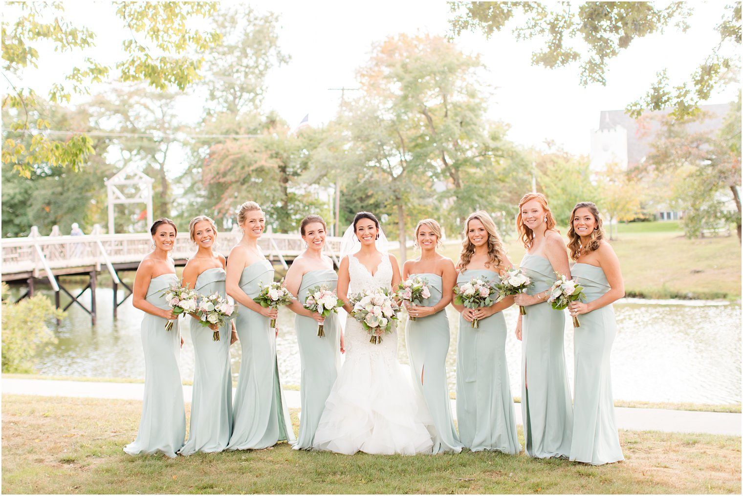 bride stands with bridesmaids in sage green gowns