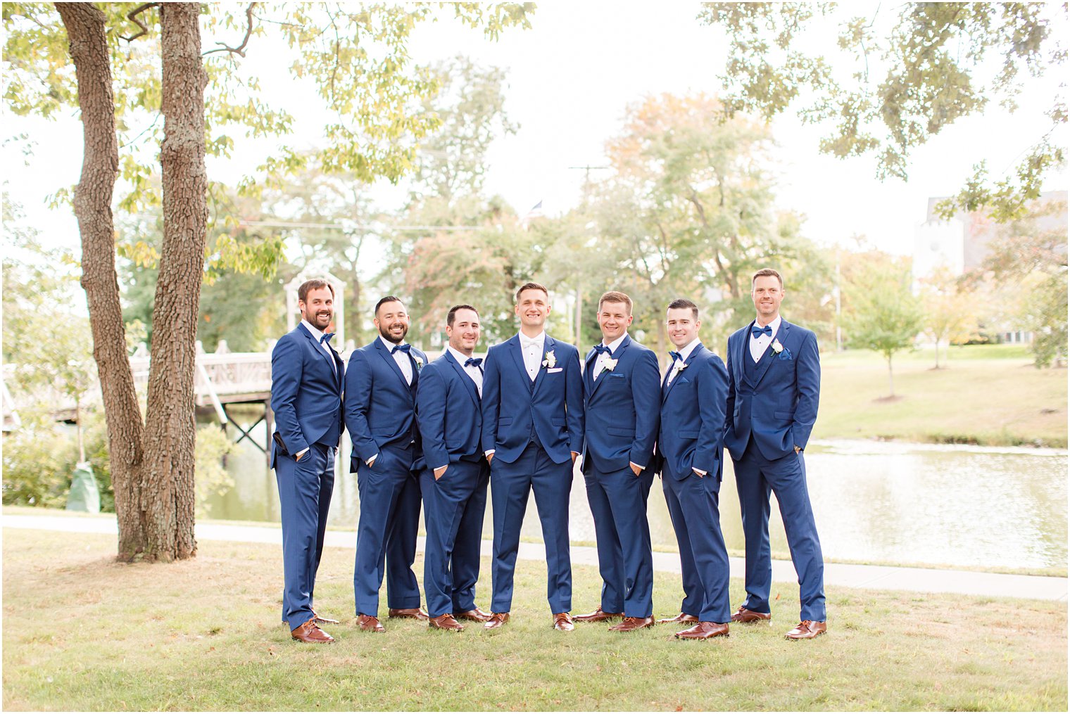 groom poses with groomsmen in navy suits