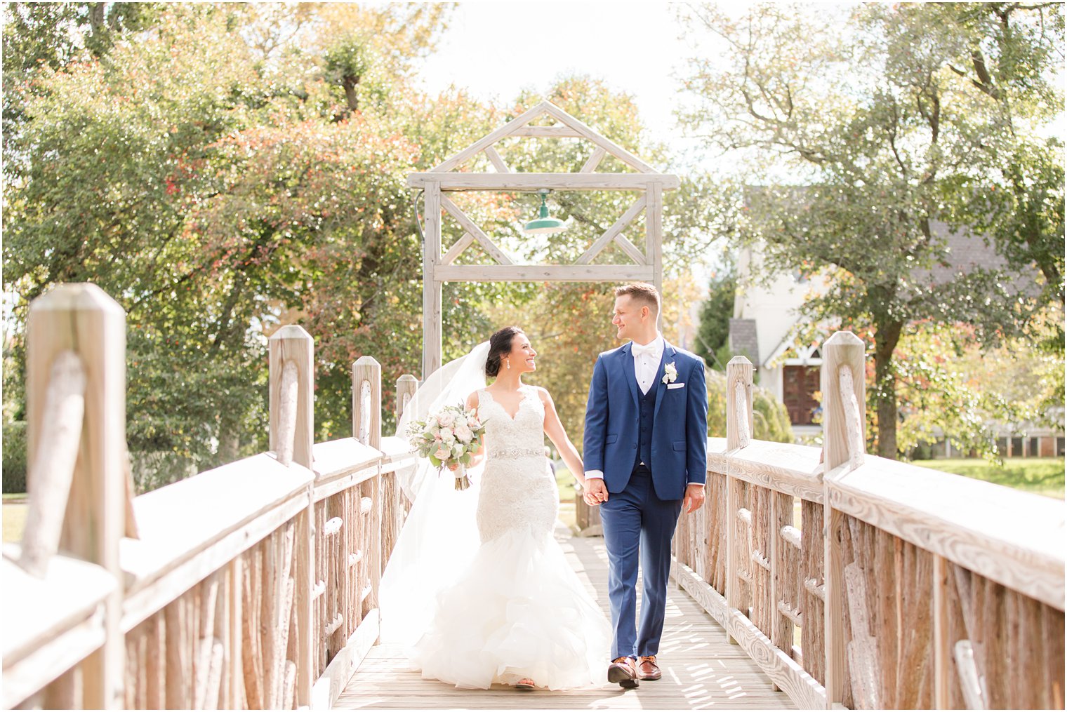 bride and groom hold hands walking over wooden bridge