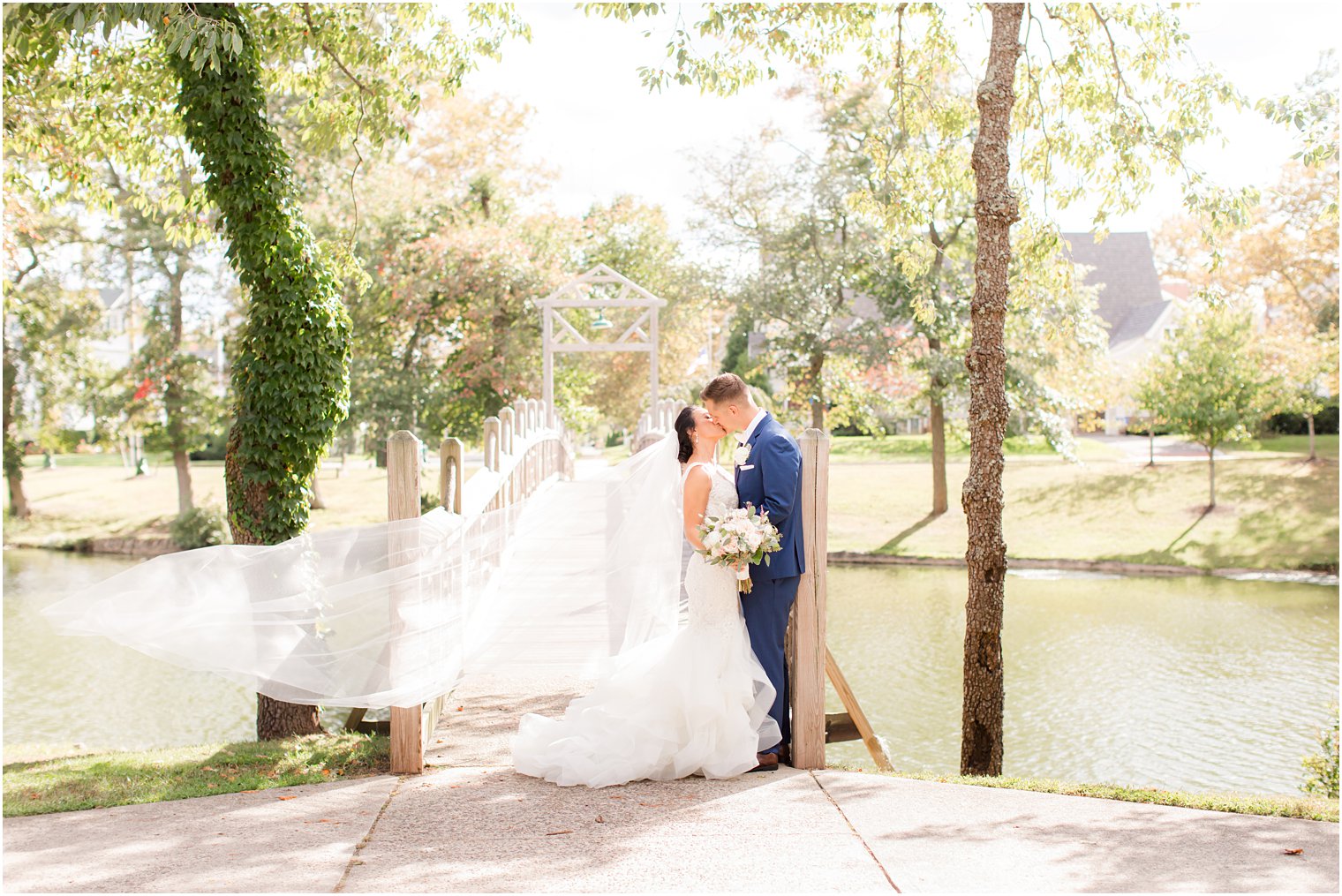 bride and groom kiss by wooden bridge in New Jersey
