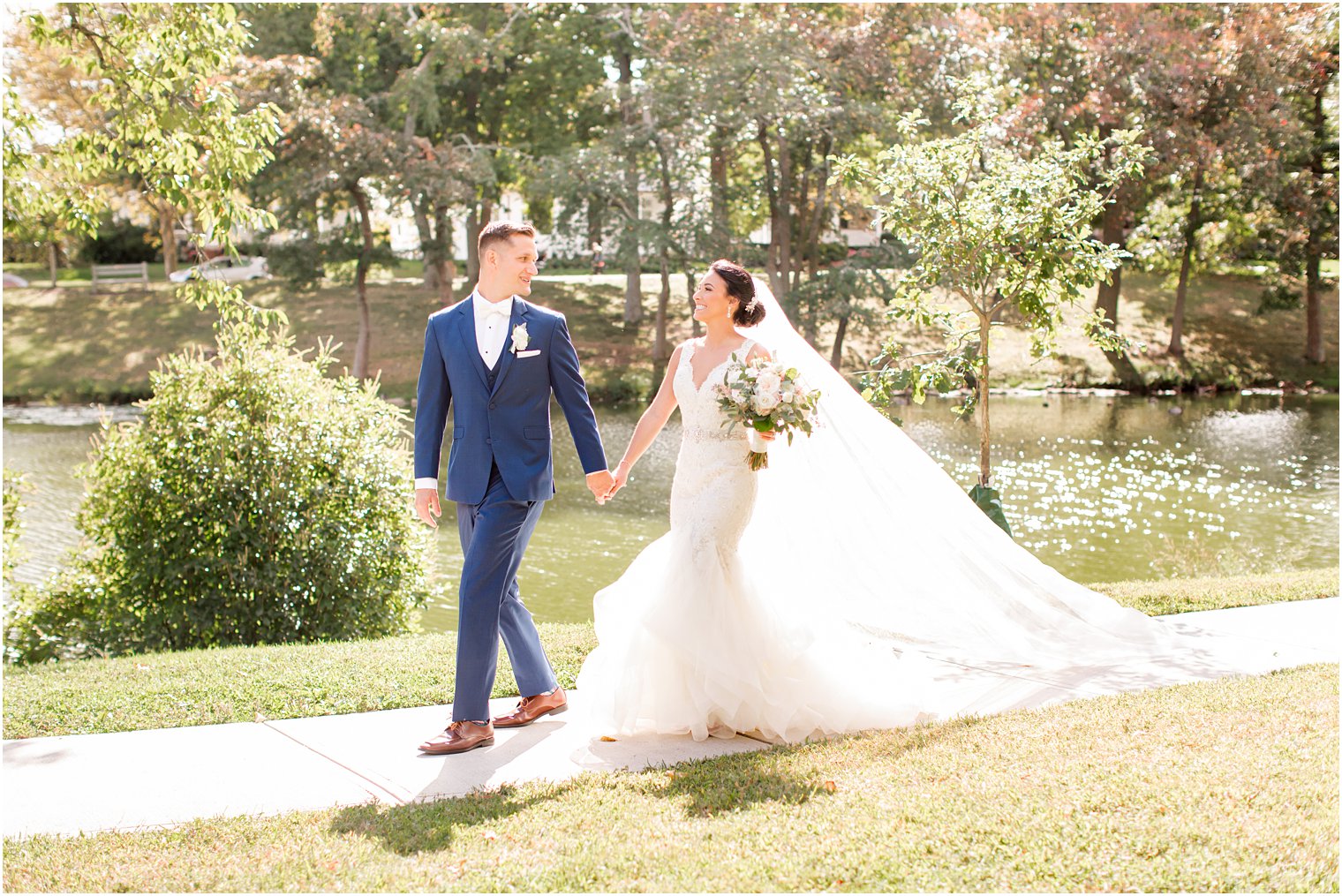 bride and groom hold hands walking through NJ park