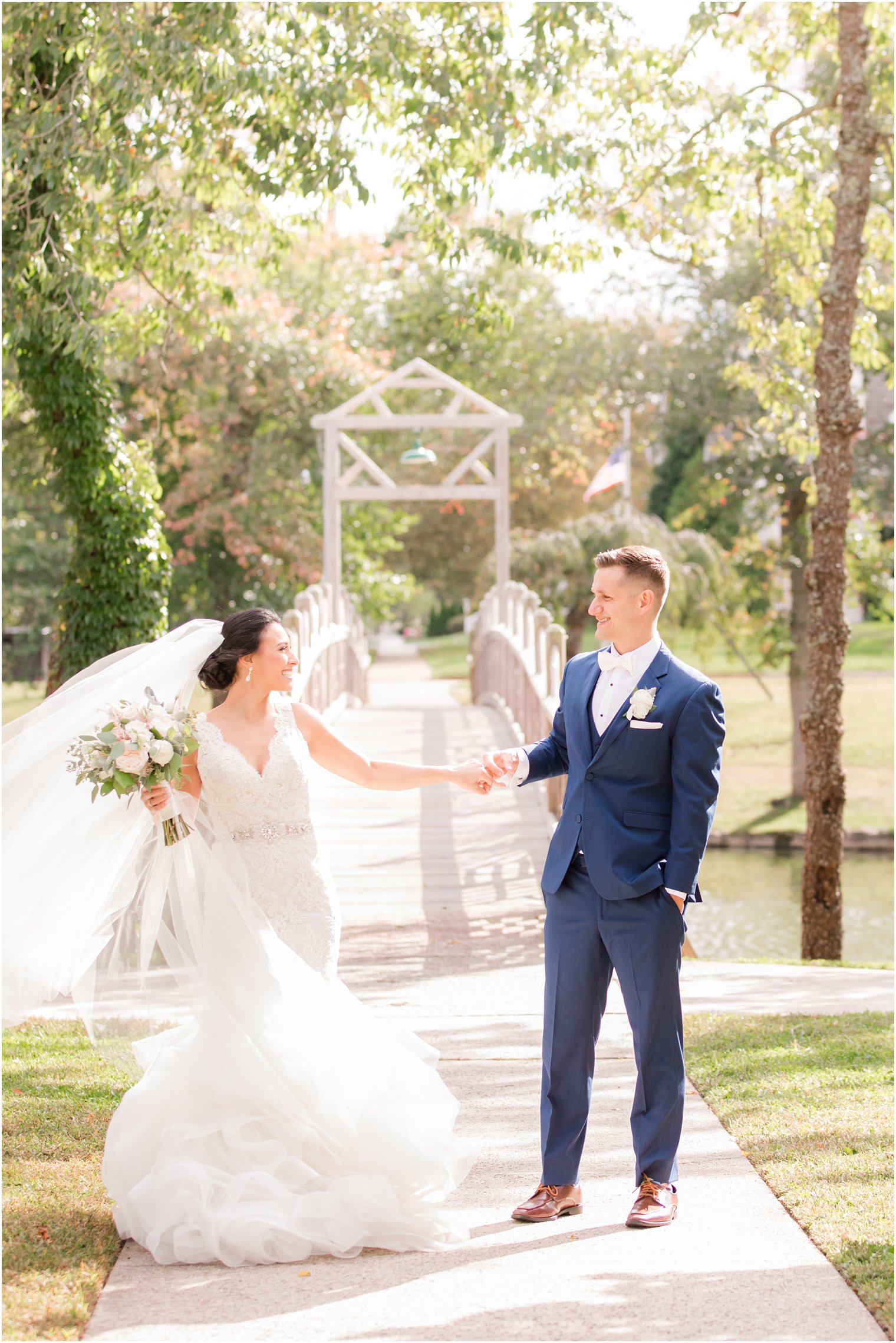 bride and groom hold hands walking over bridge in New Jersey