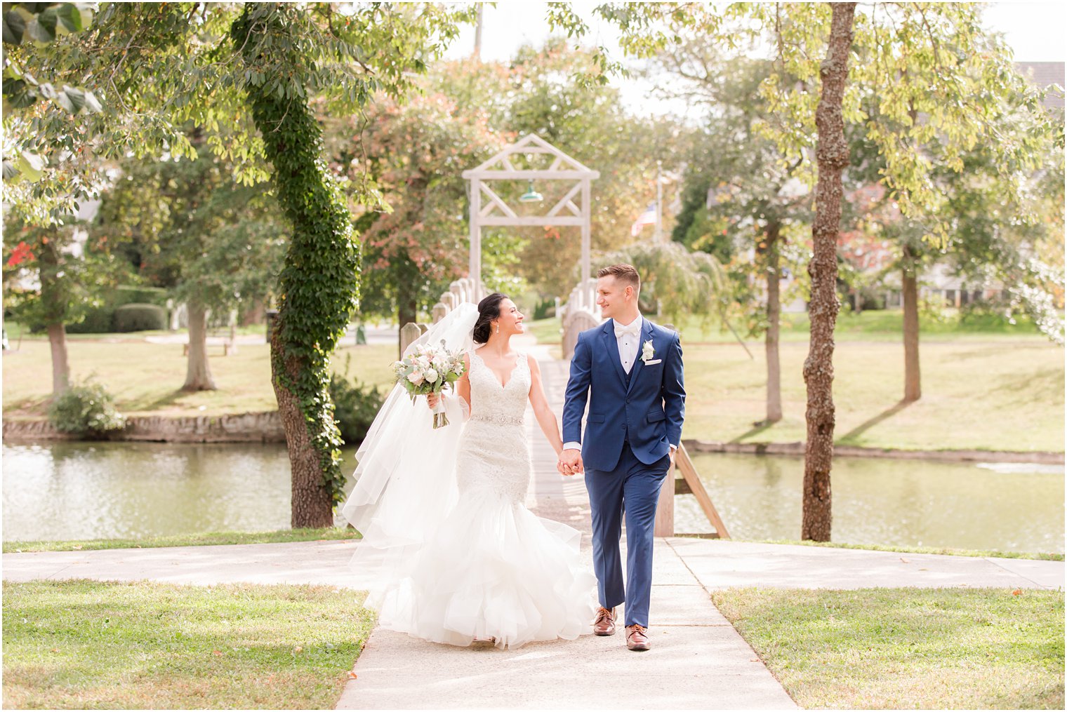 bride and groom walk over bridge in New Jersey park