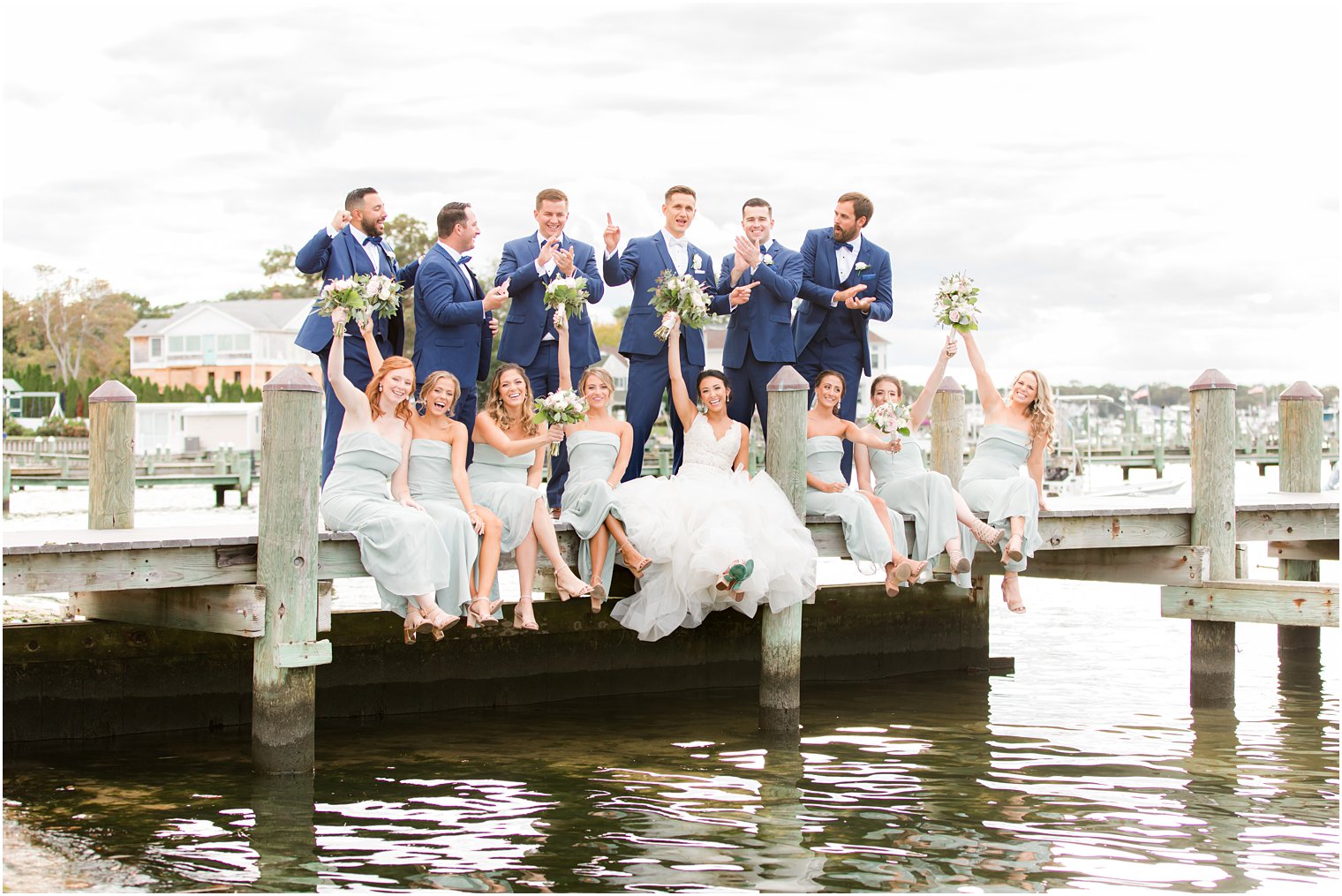 newlyweds sit with bridal party on dock at Clarks Landing