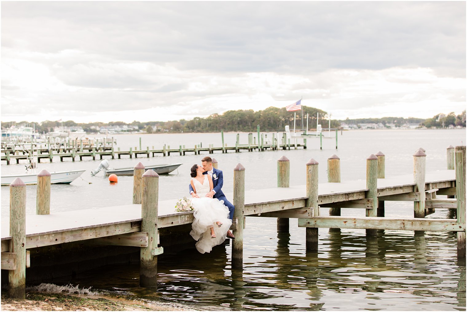 bride and groom sit on dock at Clarks Landing in Delran NJ