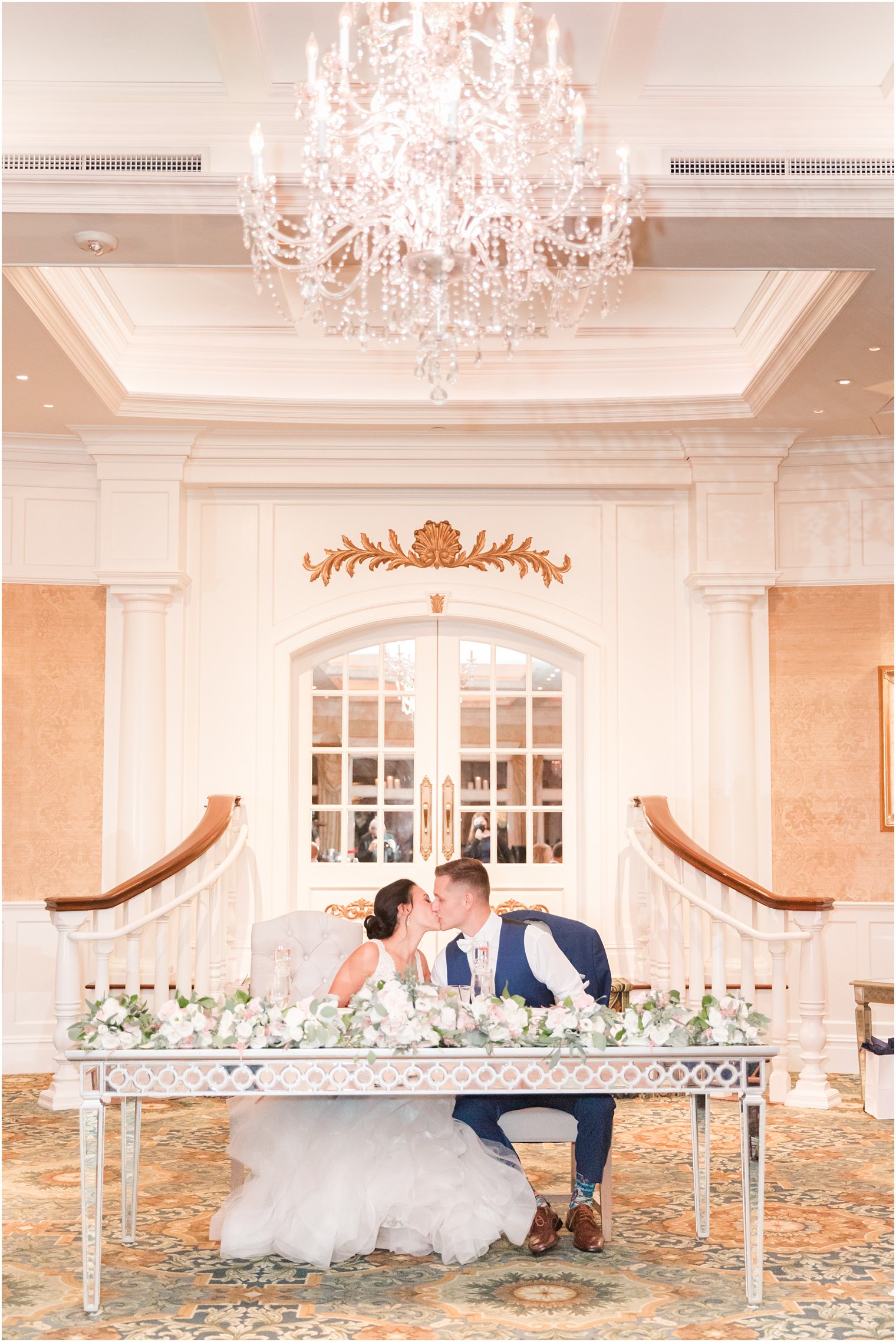 newlyweds kiss at sweetheart table during Clarks Landing wedding reception