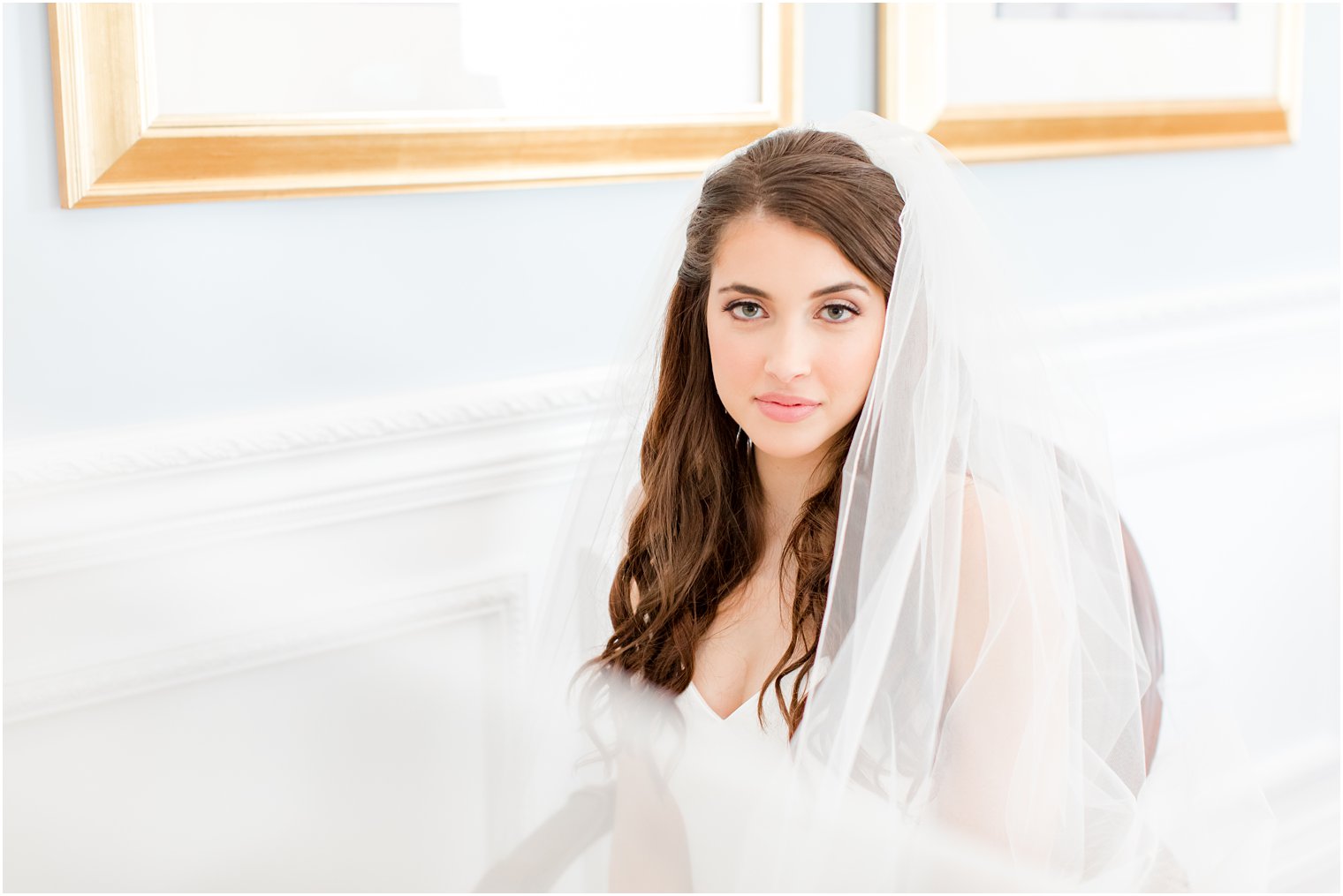 bride sits by blue wall with veil around her