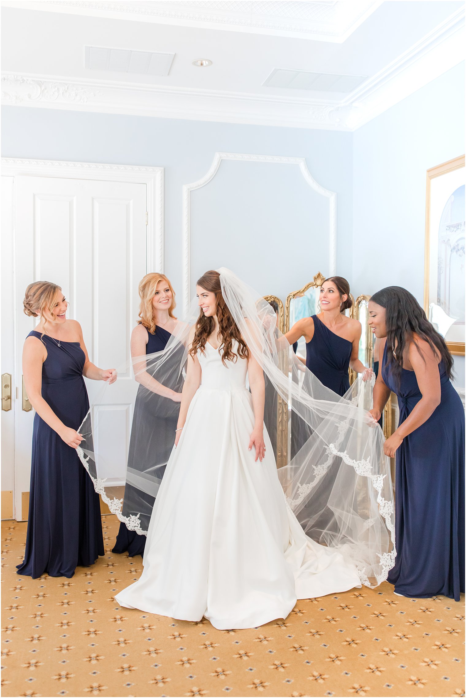 bridesmaids in navy gowns help bride prepare for Farmingdale NJ wedding