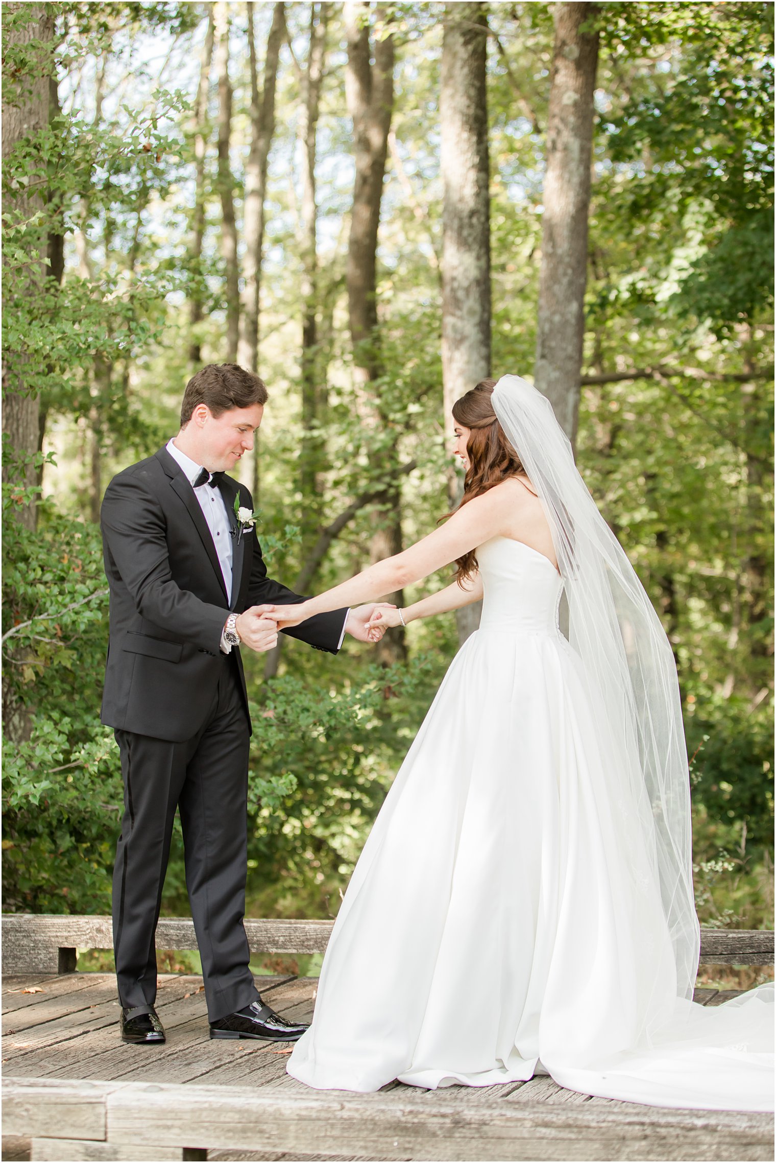 groom looks at bride's dress during first look in New Jersey