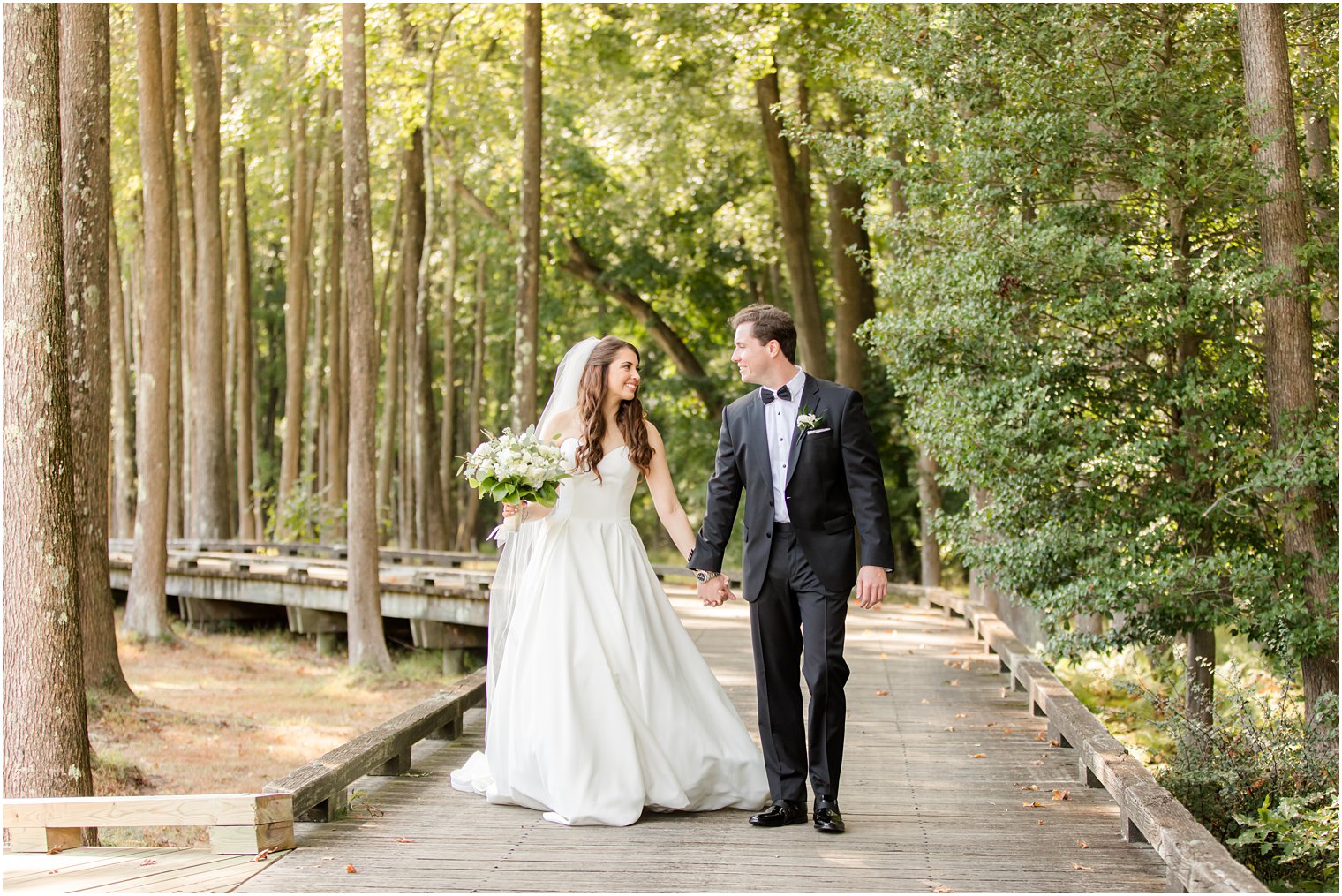 newlyweds walk on wooden path at Eagle Oaks