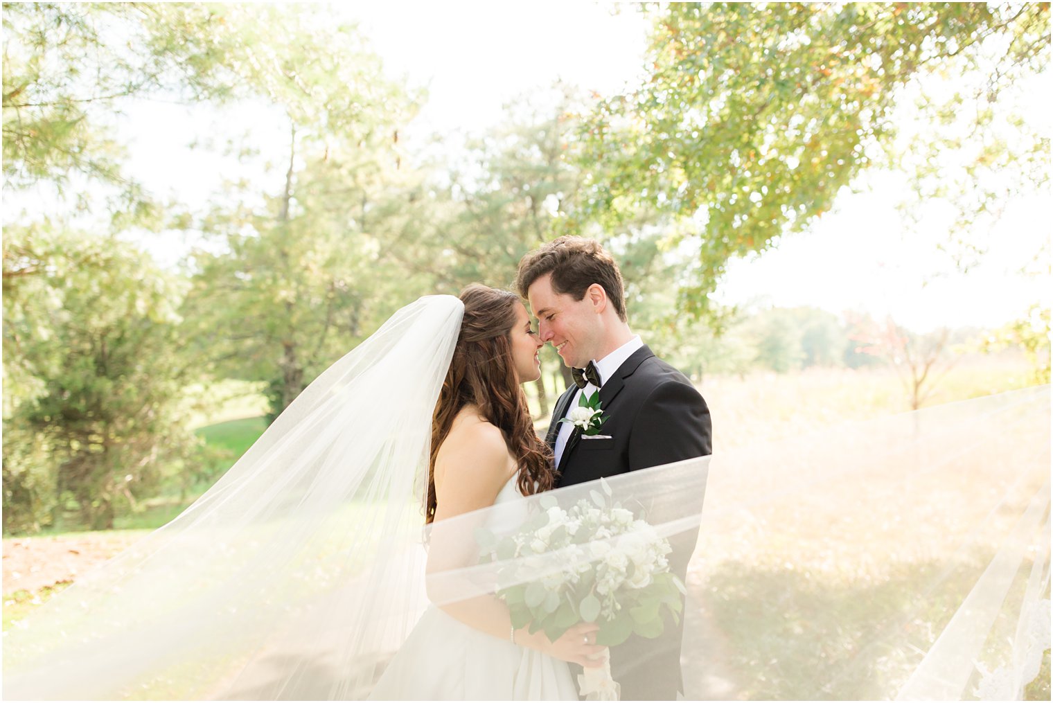 bride and groom pose with veil wrapped around them