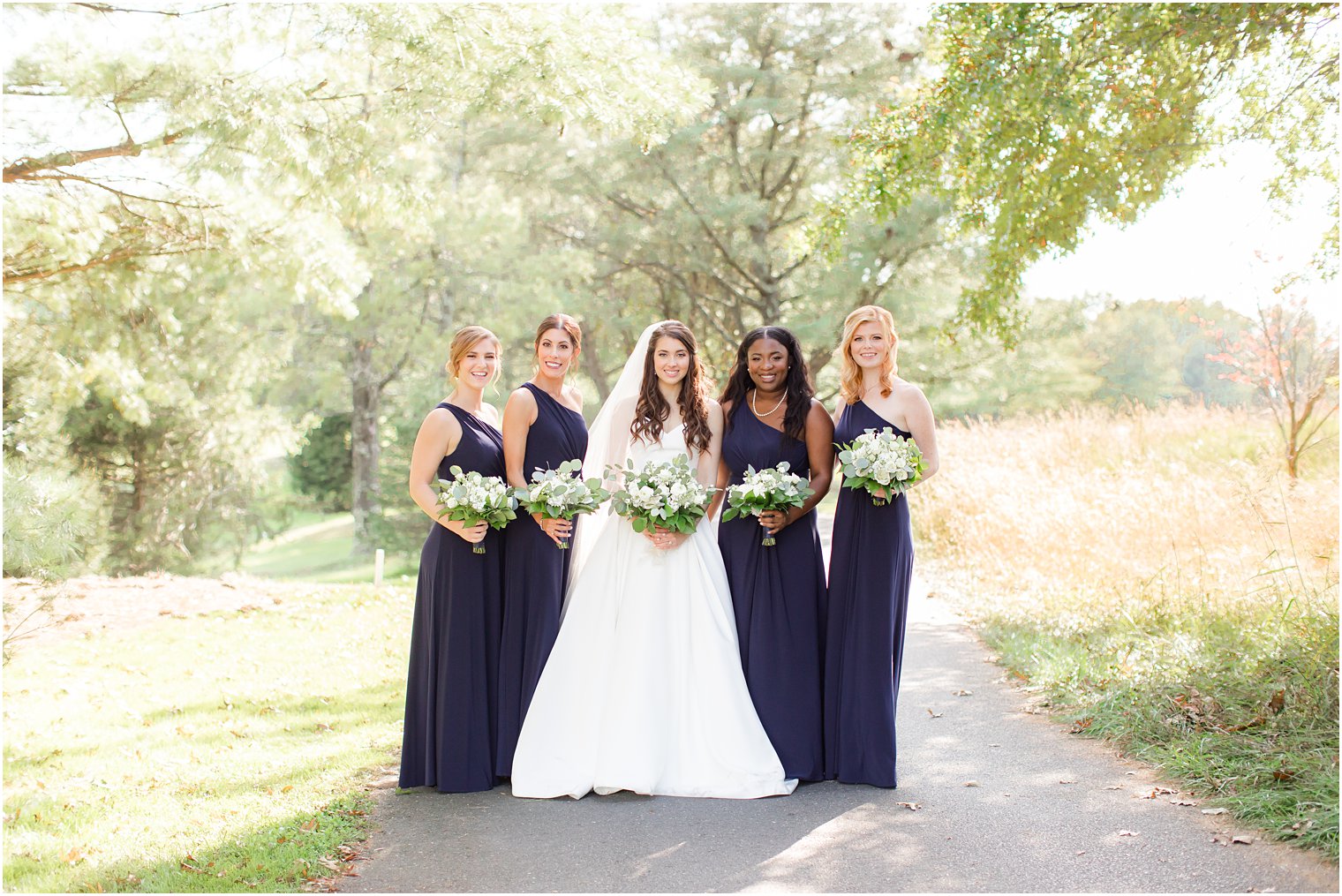 bride poses with four bridesmaids in navy gowns