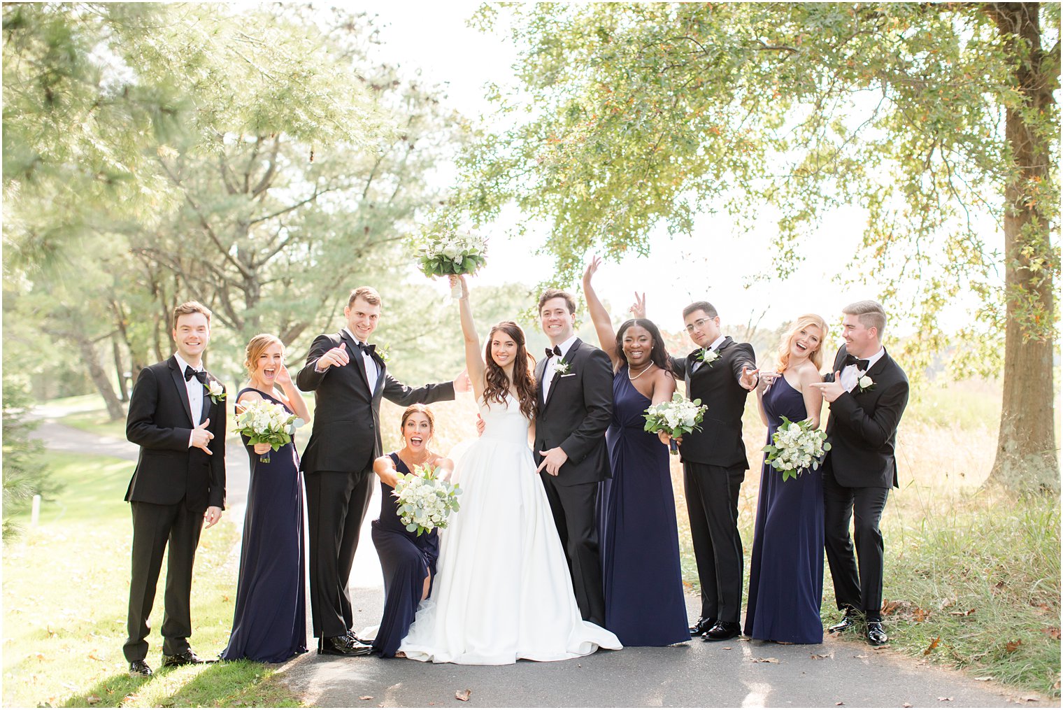 newlyweds cheer with wedding party during NJ wedding photos