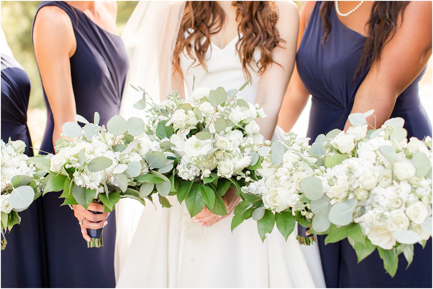 bride and bridesmaids hold out white flowers in New Jersey