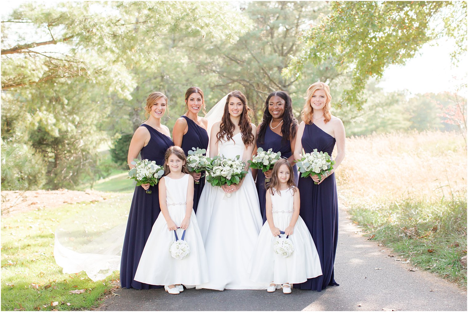 bride poses with bridesmaids in navy gowns