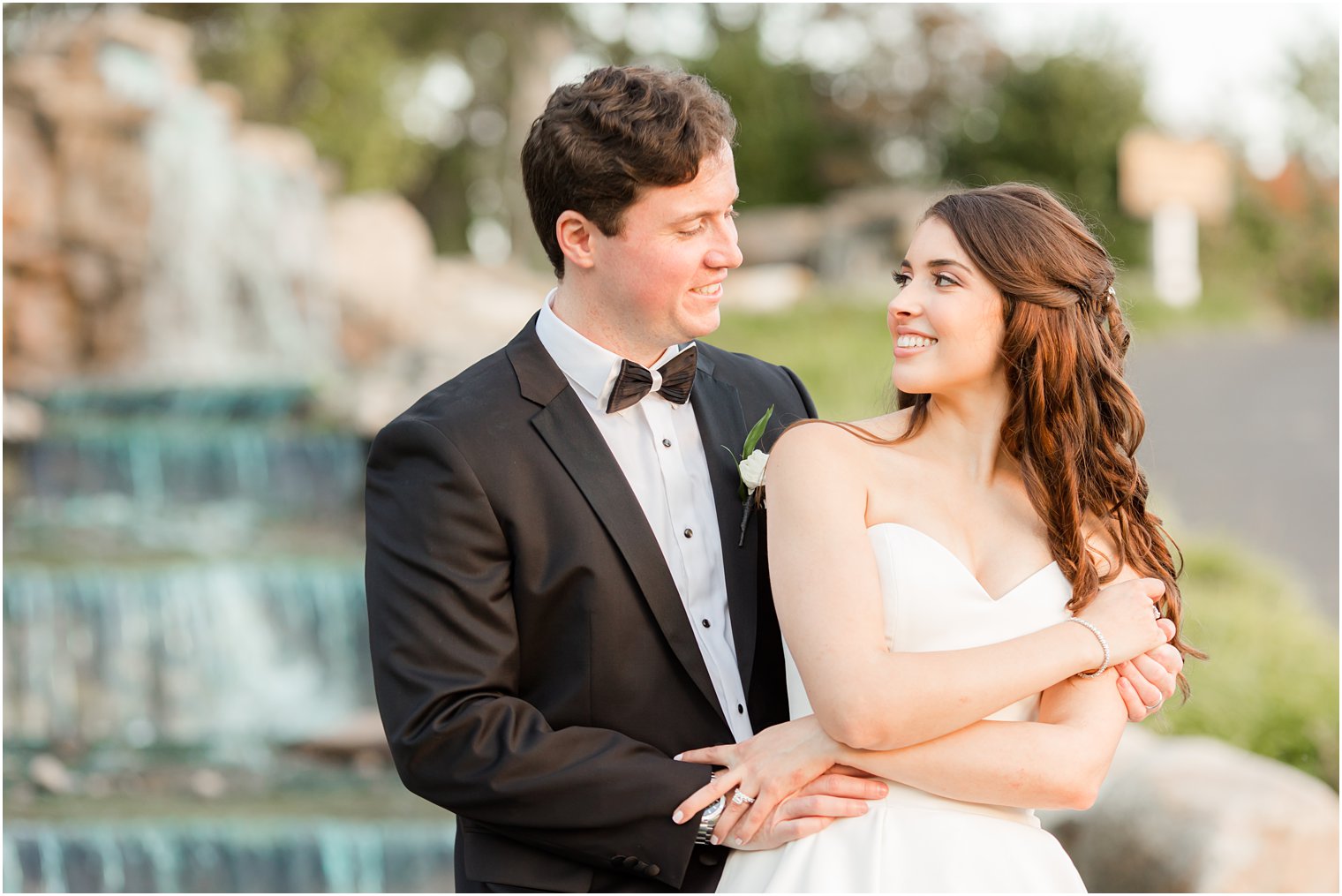 newlyweds hug by fountain at Farmingdale NJ